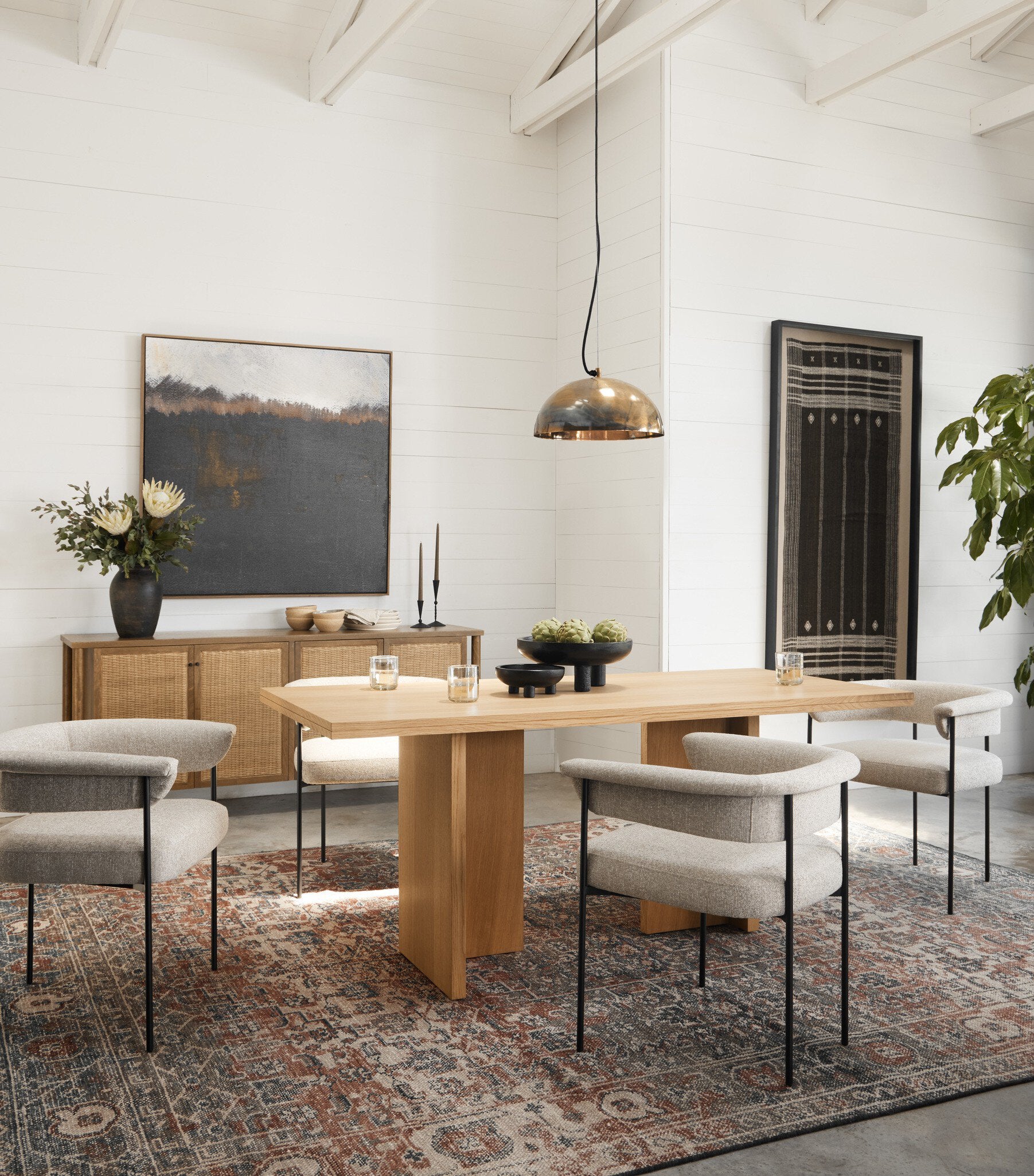 Modern dining room with wooden table, chairs, Wooden sideboard with rattan doors and decorative elements.