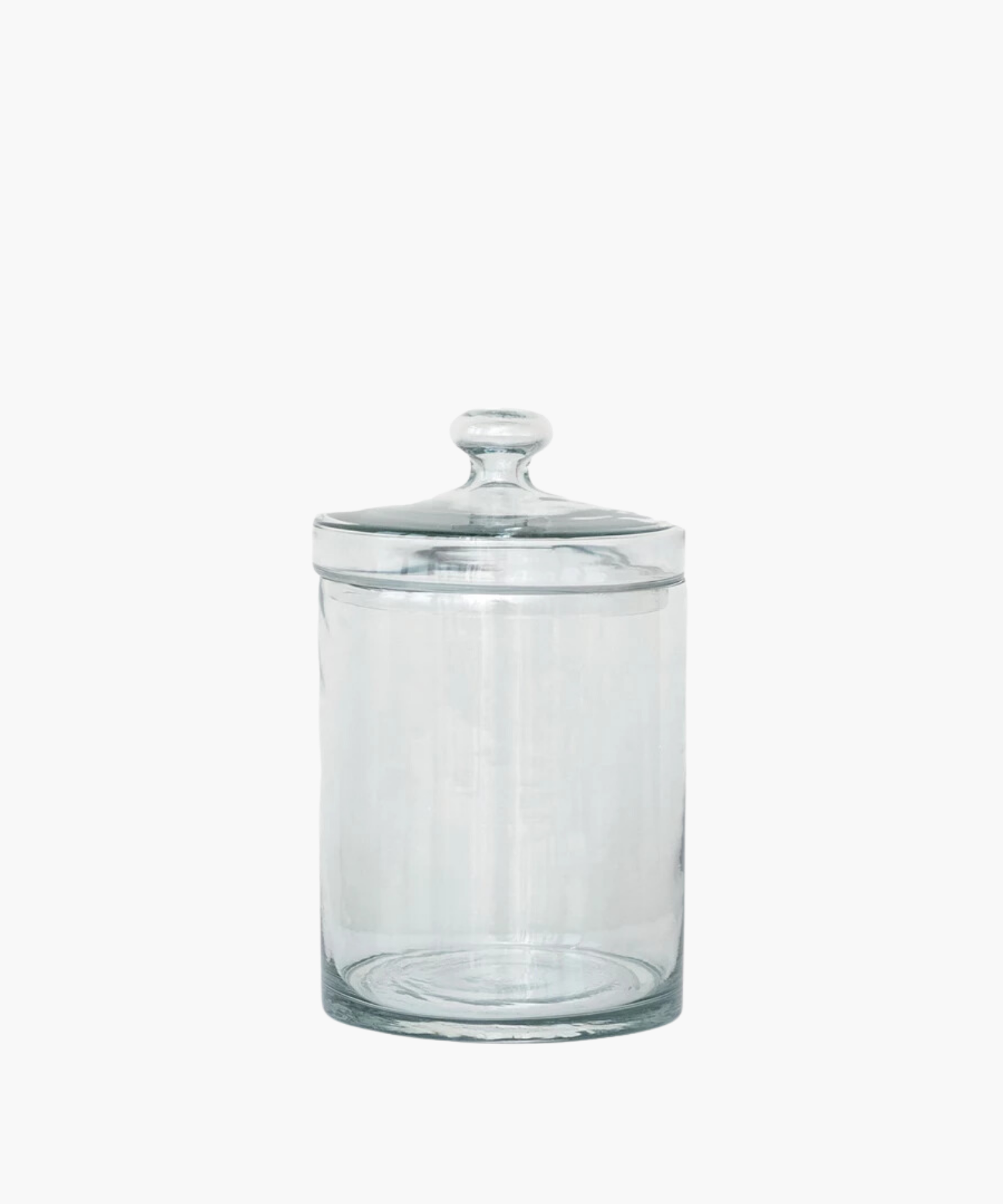 A transparent glass jar with a rounded lid is centered on a white background. The jar is empty and reflects light softly, conveying simplicity and elegance. | Wildwood Home Co.