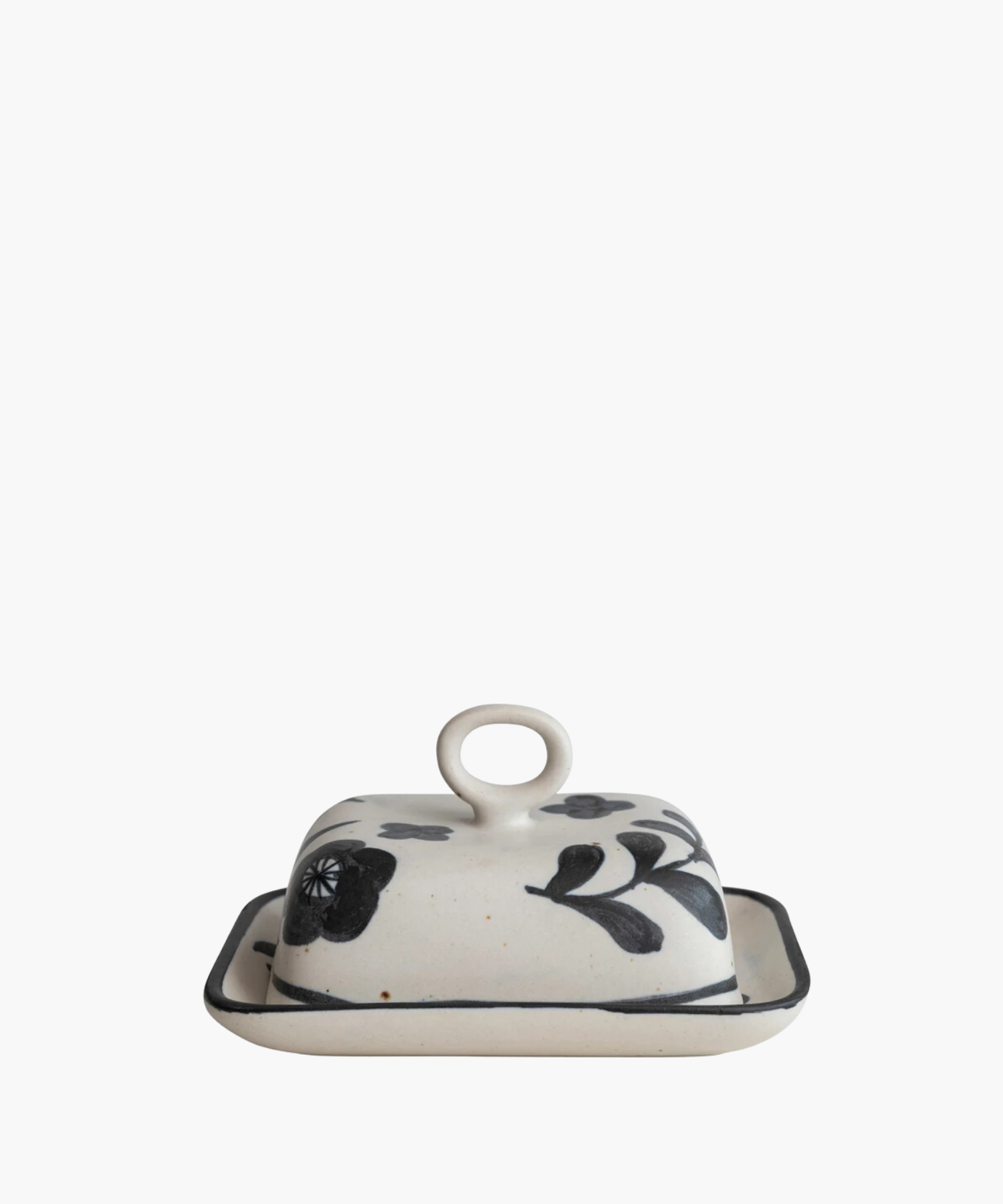 Ceramic butter dish with a lid featuring black floral designs and a circular handle, set against a plain white background. The tone is elegant and artistic. | Wildwood Home Co.