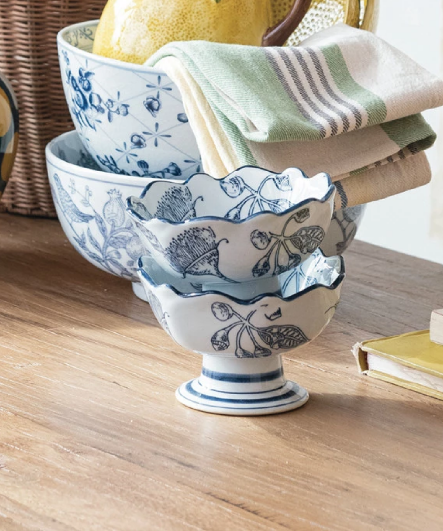 Two Elegant bowls with a wavy rim, decorated with intricate blue floral designs stacked together and styled with kitchen accessories. | Wildwood Home Co.