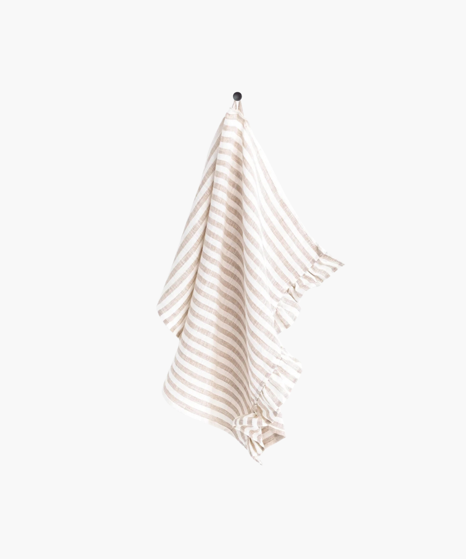 A beige and white striped linen tea towel with ruffle trim hangs neatly on a black hook against a plain white background, creating a clean and minimalistic appearance. | Wildwood Home Co.