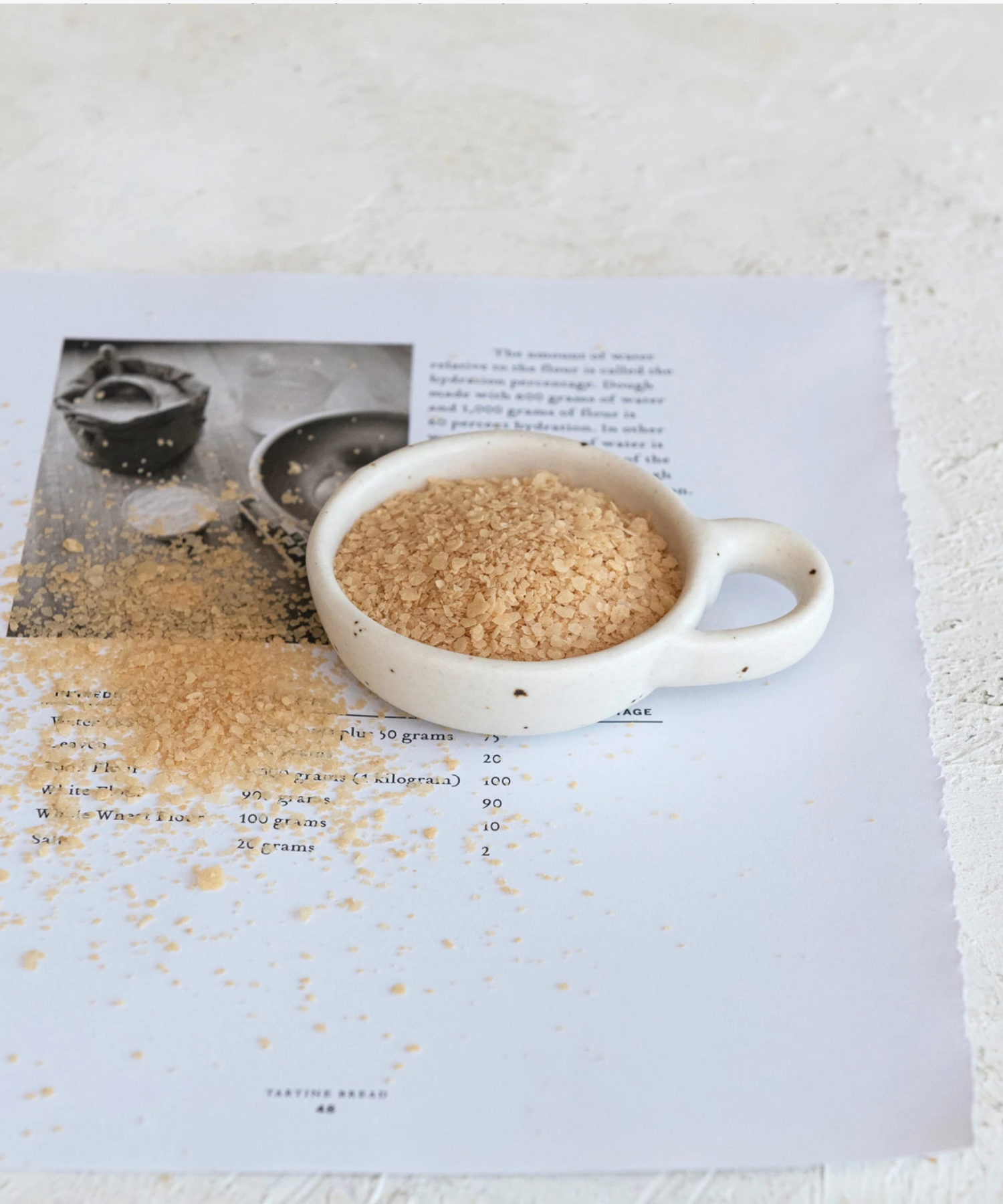 Minimalist ceramic bowl with speckled texture and a round handle on the right side. Its earthy tones convey simplicity and elegance. | Wildwood Home Co.