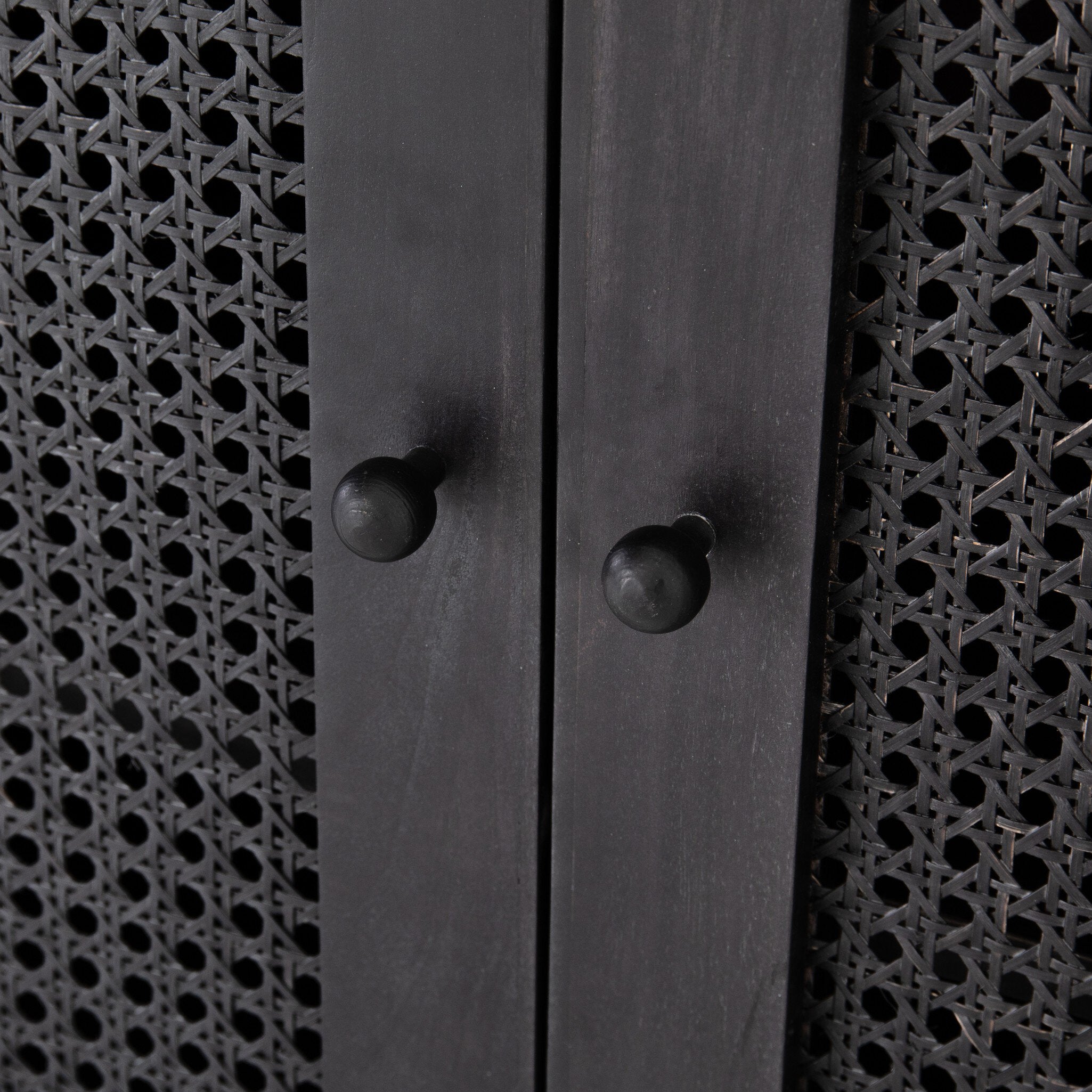Close-up of the black tilde sideboard with two knobs and arched cane door panels.