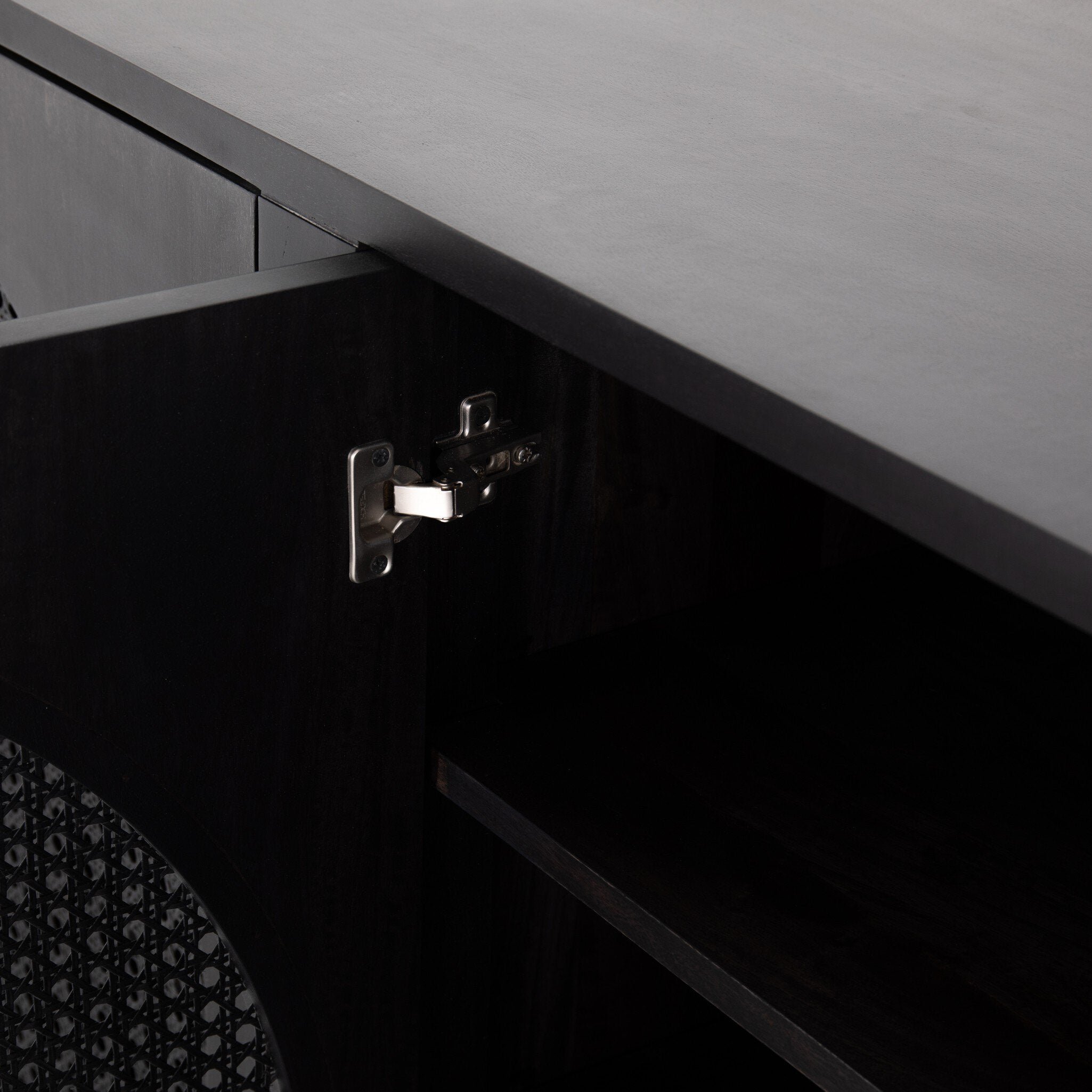 Close-up of a cabinet hinge on a black cabinet.