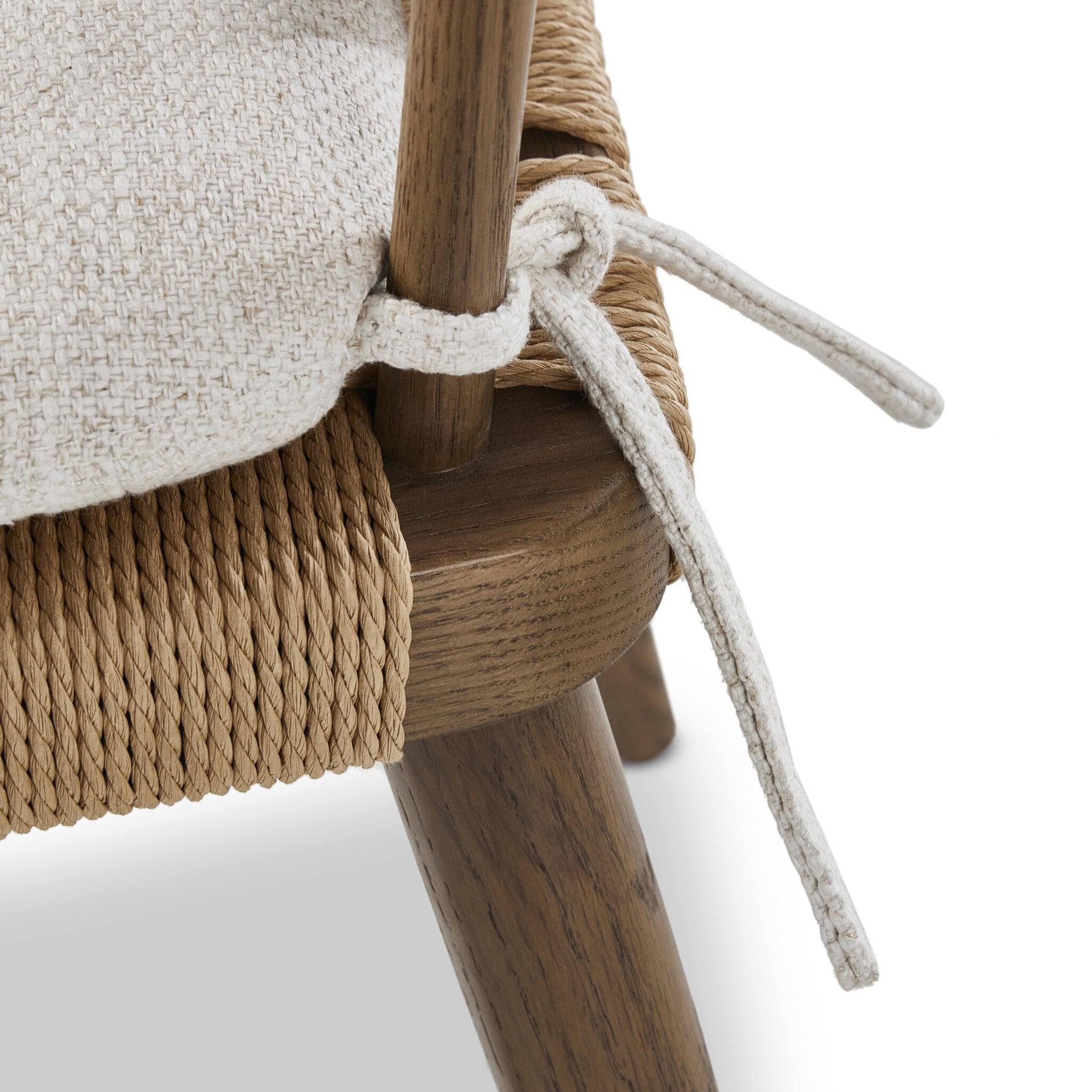 Close-up of a wooden chair with beige fabric and white rope detail on a white background