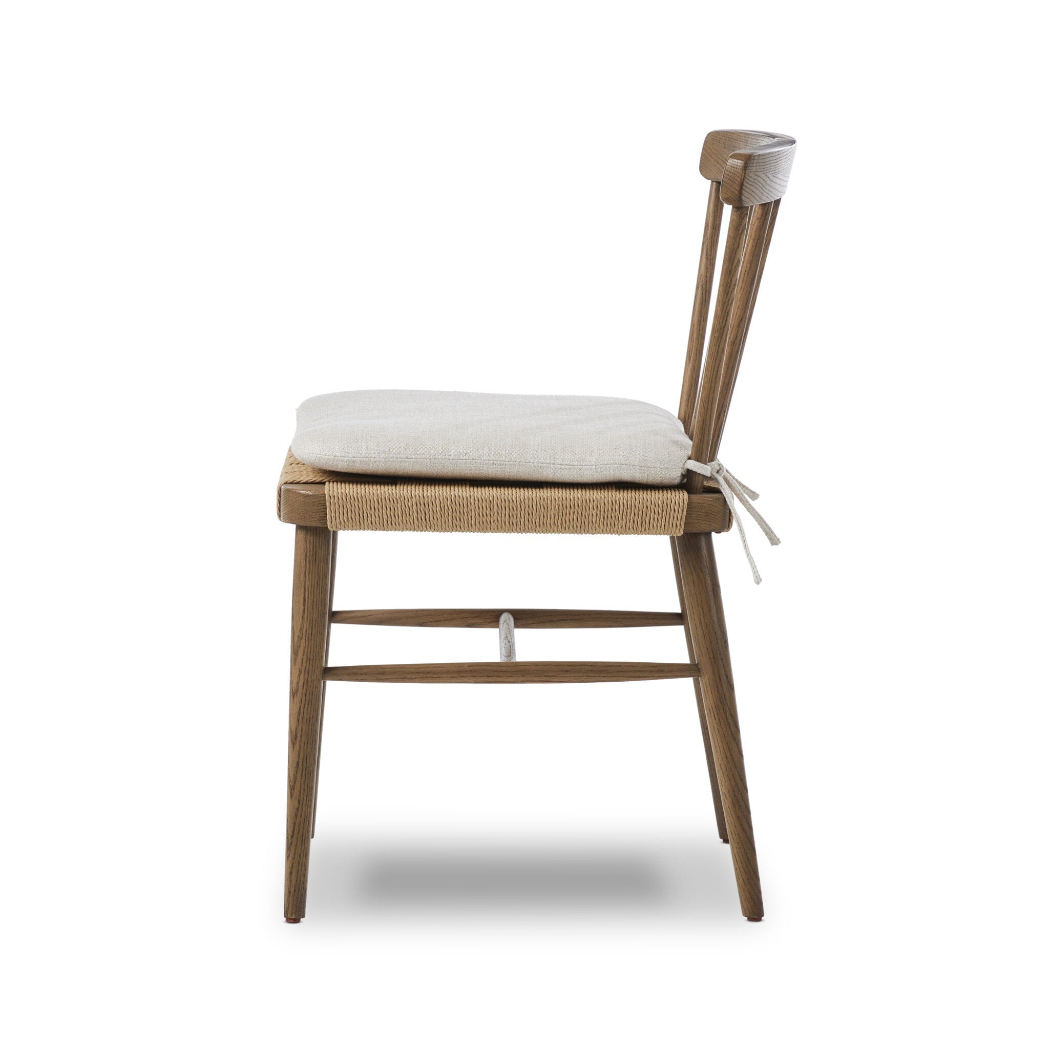 Wooden chair a spindle back, grid-woven seat, and a white cushion on a white background.