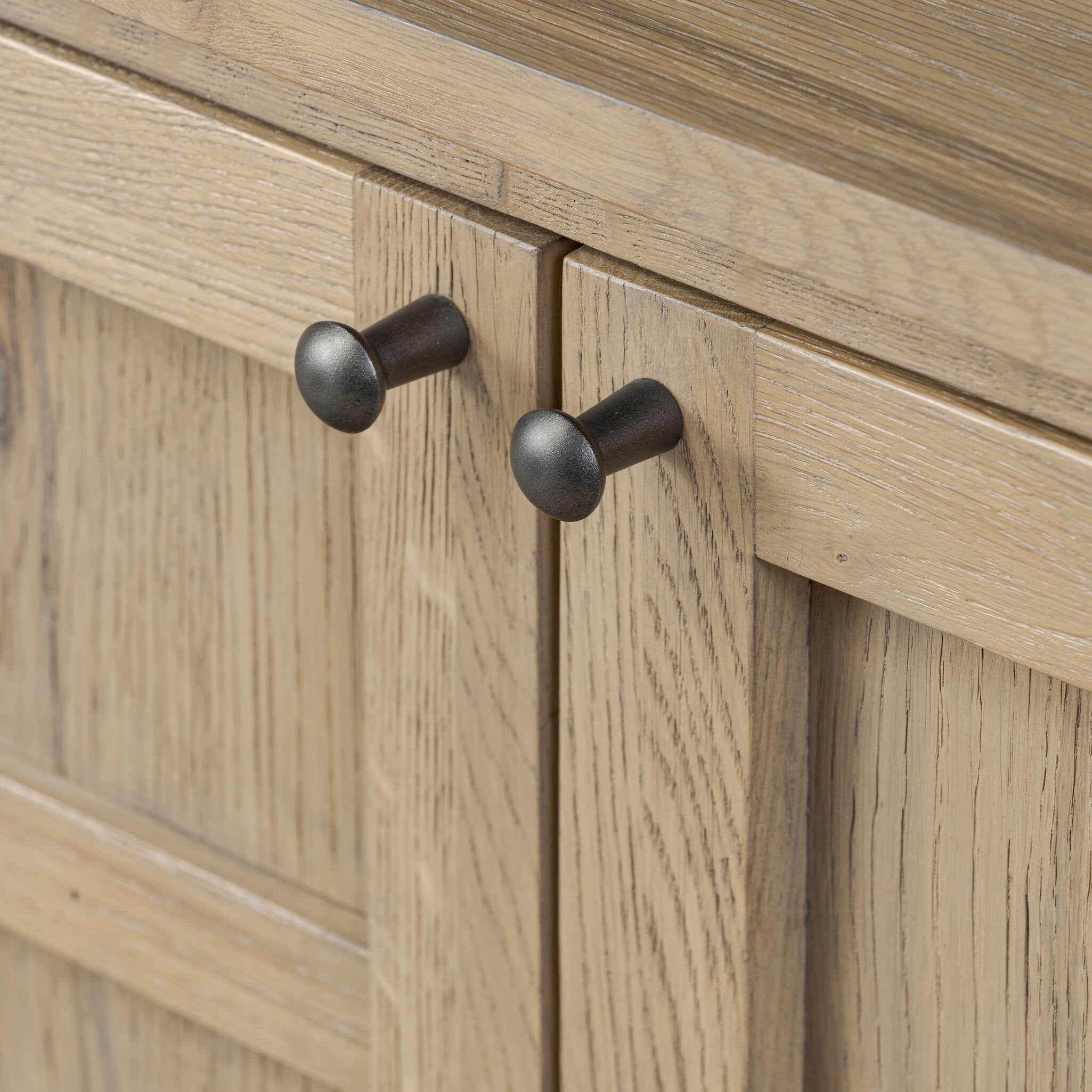 Close up of Handles of a wooden sideboard with a grid like pattern on the doors on a white background.