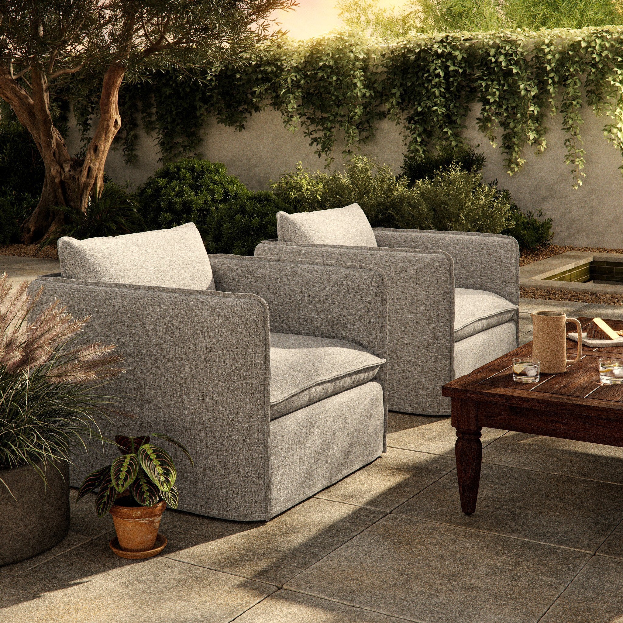 Outdoor patio setting with gray swivel armchairs and a wooden coffee table. | Wildwood Home Co.