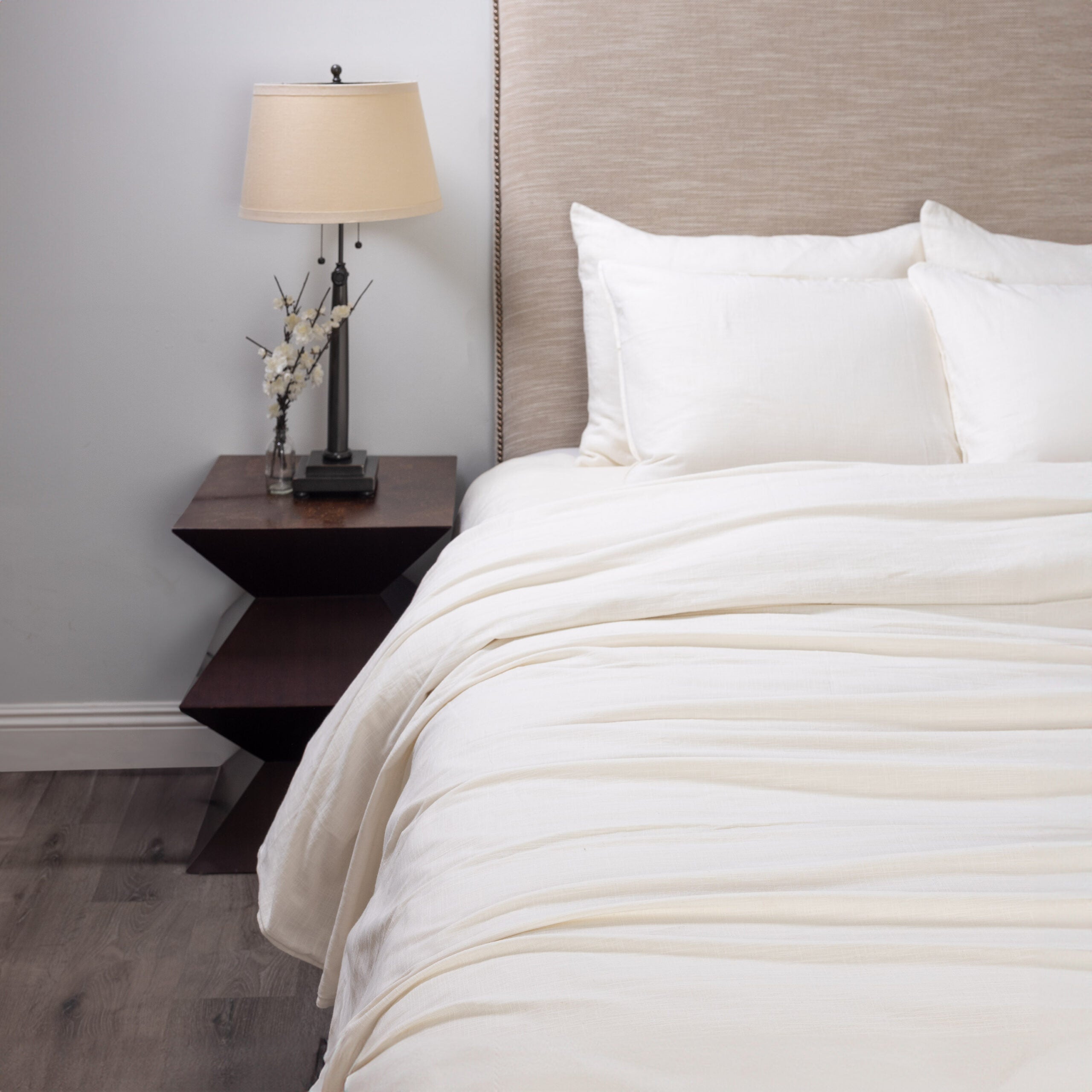 Neatly made bed with neutral linen bedding in a bedroom setting. | Wildwood Home Co.
