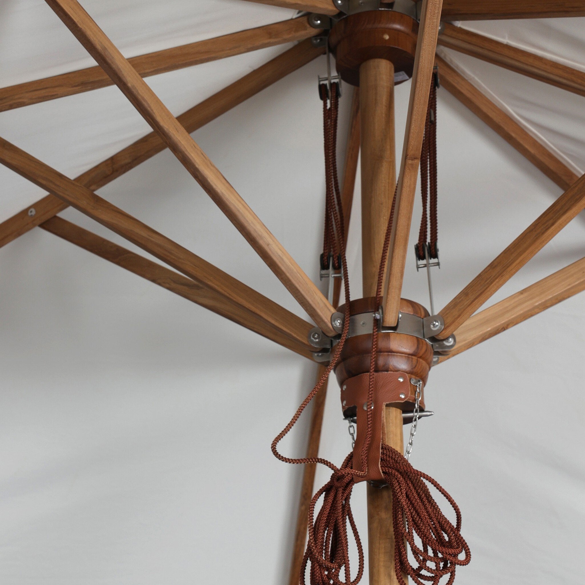 Close-up of the teak umbrella frame with leather detailing and a woven rope cord. 