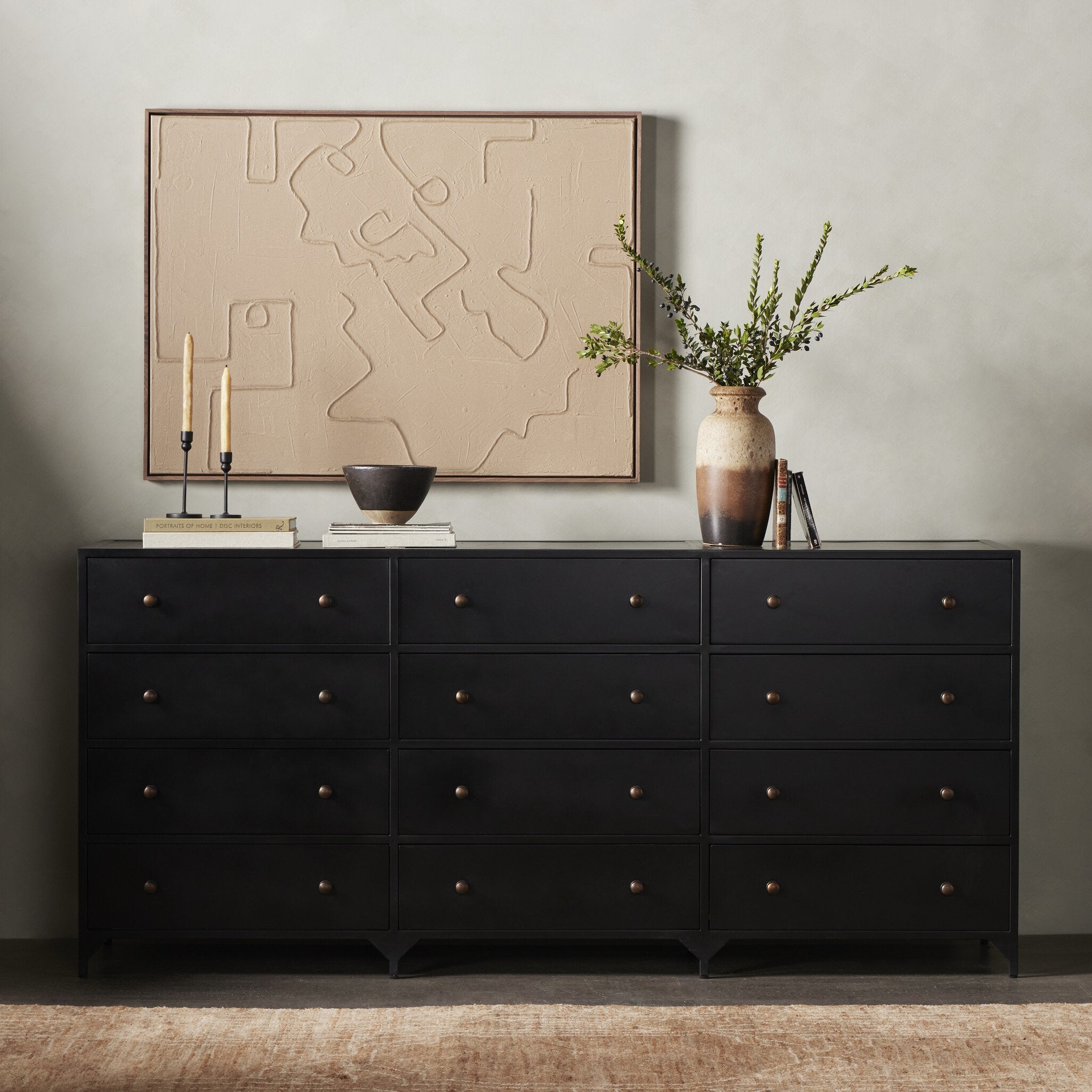Black dresser with decorative items including a map, candles, and a vase against a neutral wall. | Wildwood Home Co.