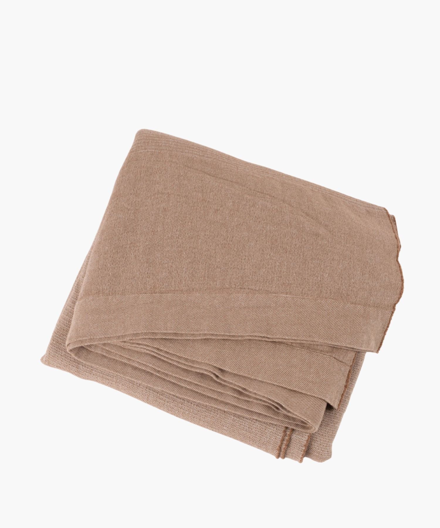 Neatly folded camel-colored knit throw with finely woven texture and subtle ribbed border on white background.