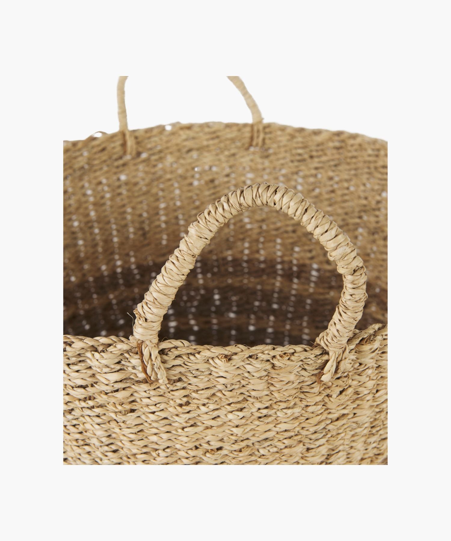 Close up of a woven seagrass basket in a natural and brown tone with two loop handles and subtle striped accents. The basket has a simple, rustic design.