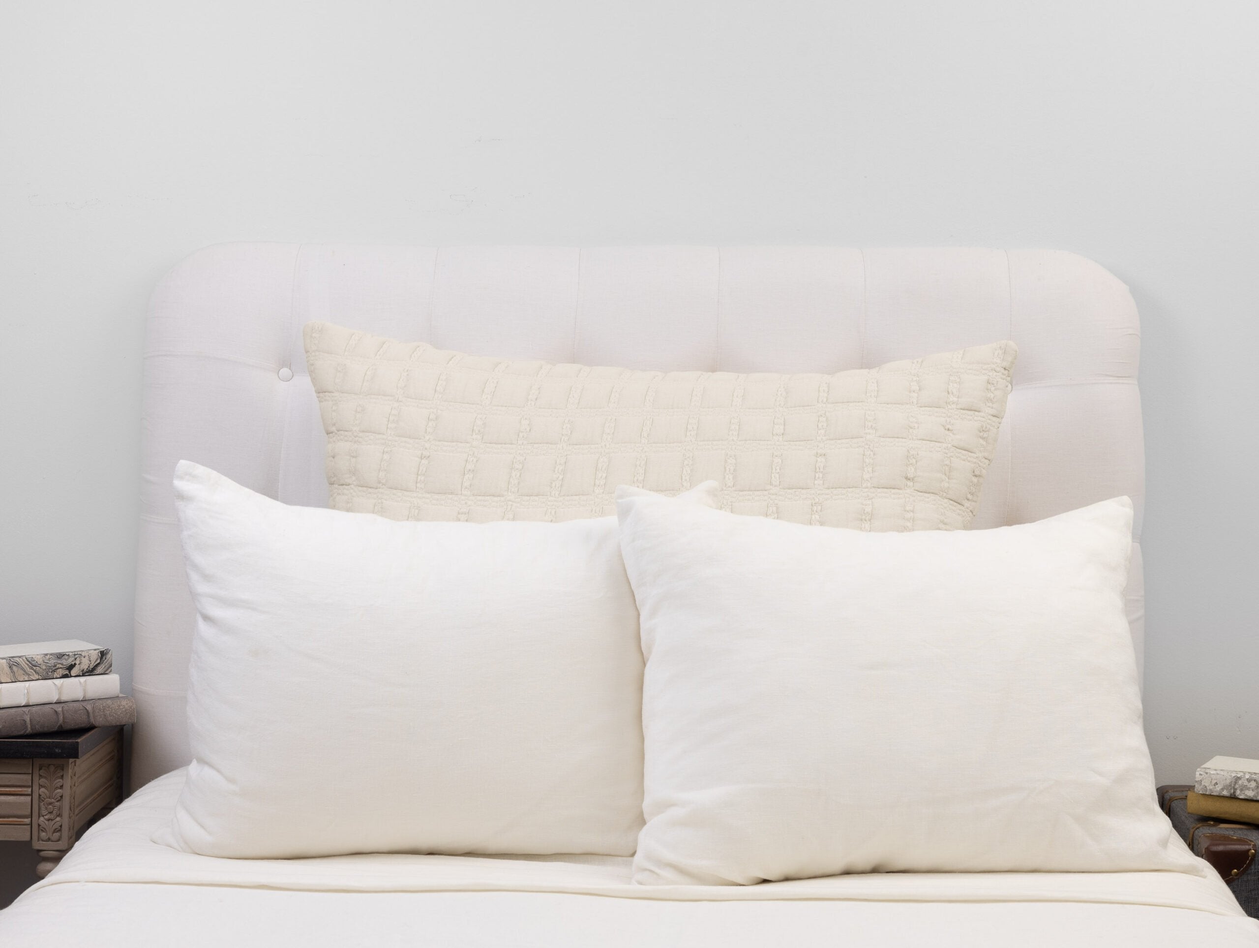 Cream sham styled with white pillows, showing its structured texture and refined grid quilting.