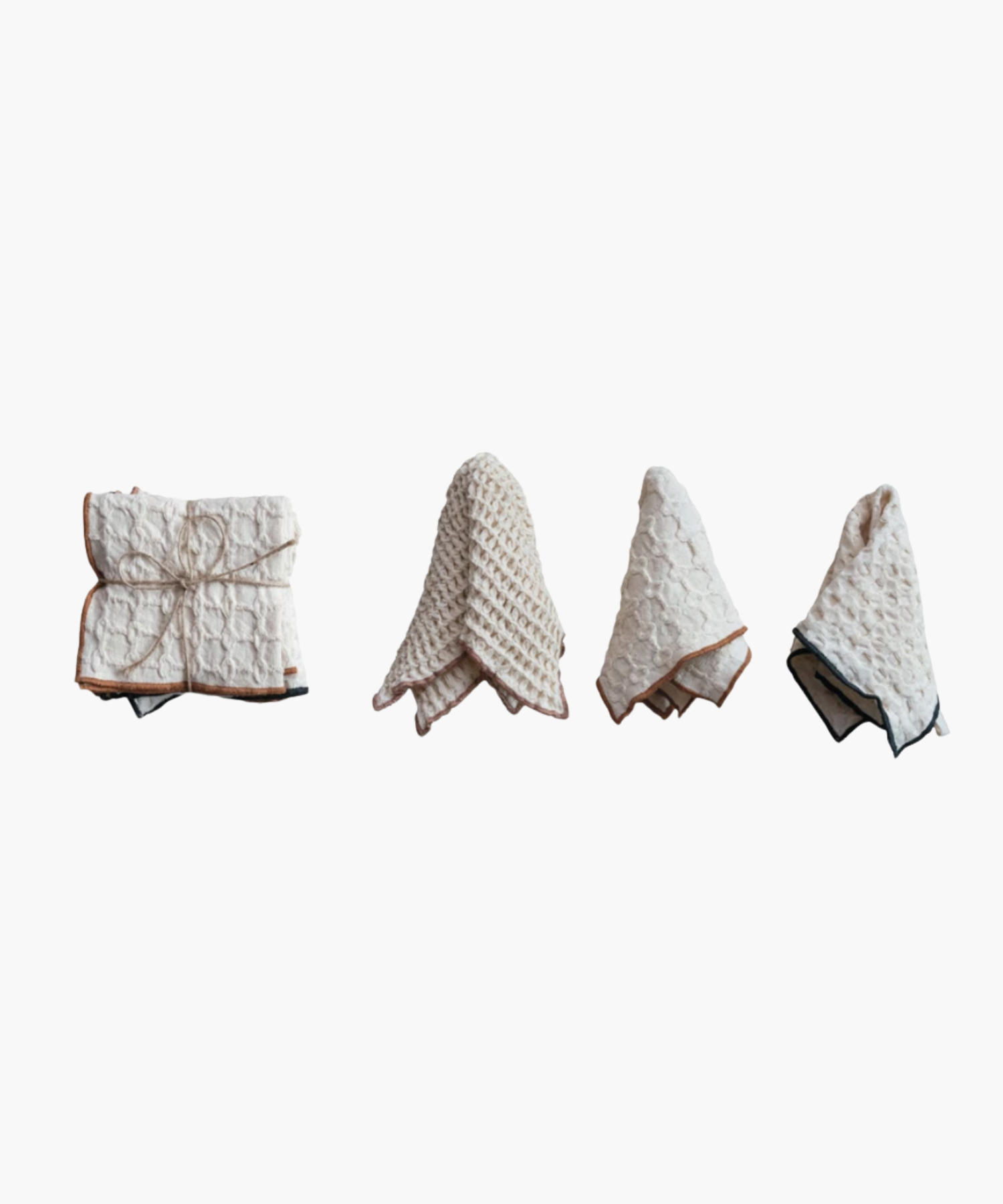 Four waffle-textured cloths are displayed against a white background. One is neatly folded and tied with twine; the others are variously draped. | Wildwood Home Co.