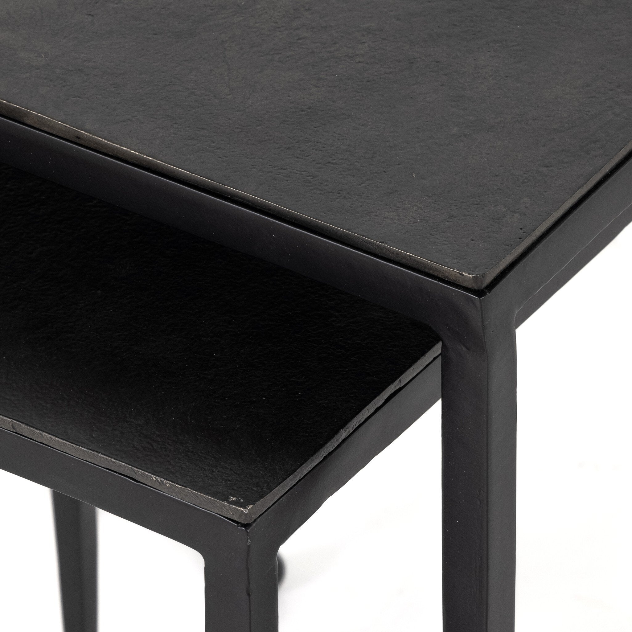 Two black nesting tables with tapered legs and squared off aluminum tops on a white background.