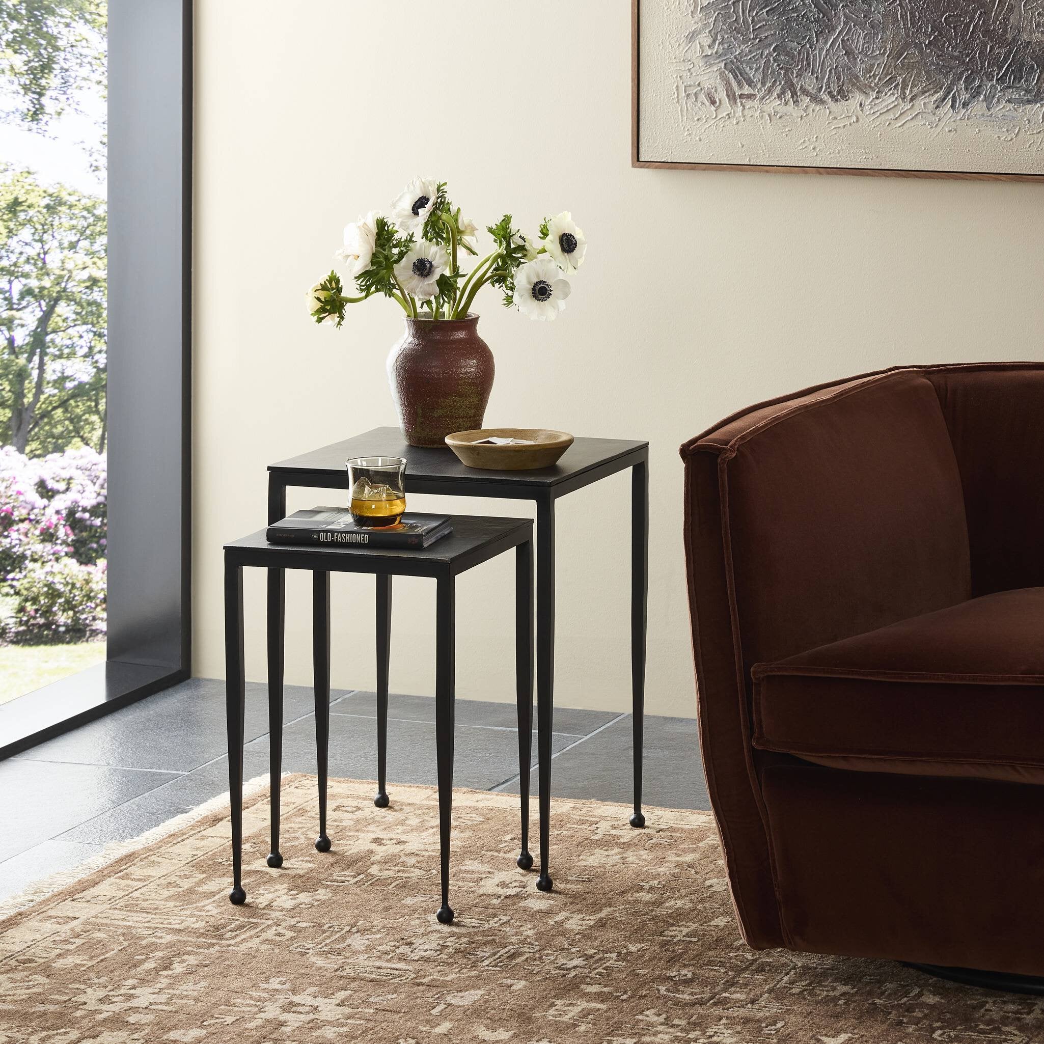 Black nesting tables with decorative items in a living room setting.