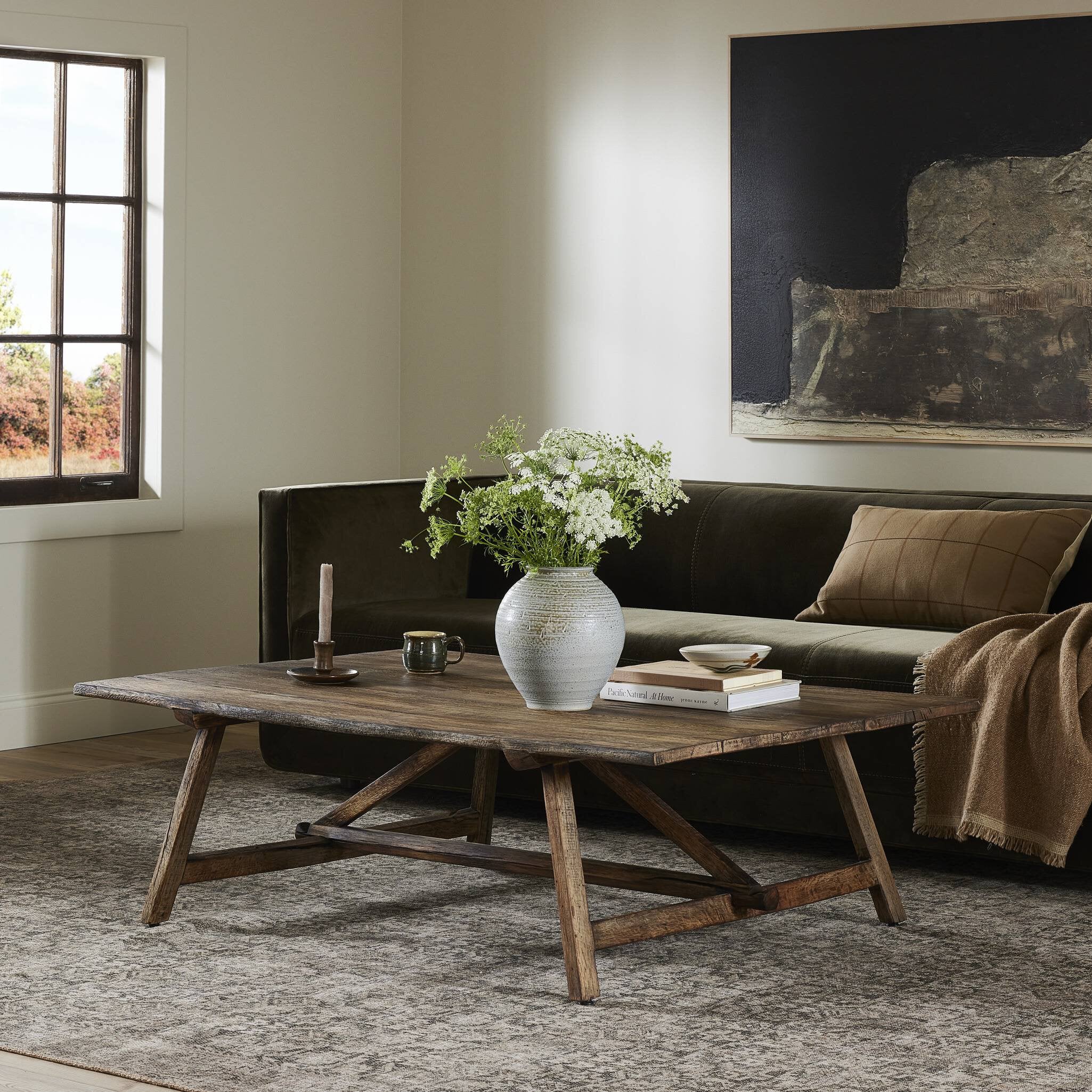 Living room with a wooden coffee table, vase with flowers, and books. | Wildwood Home Co.
