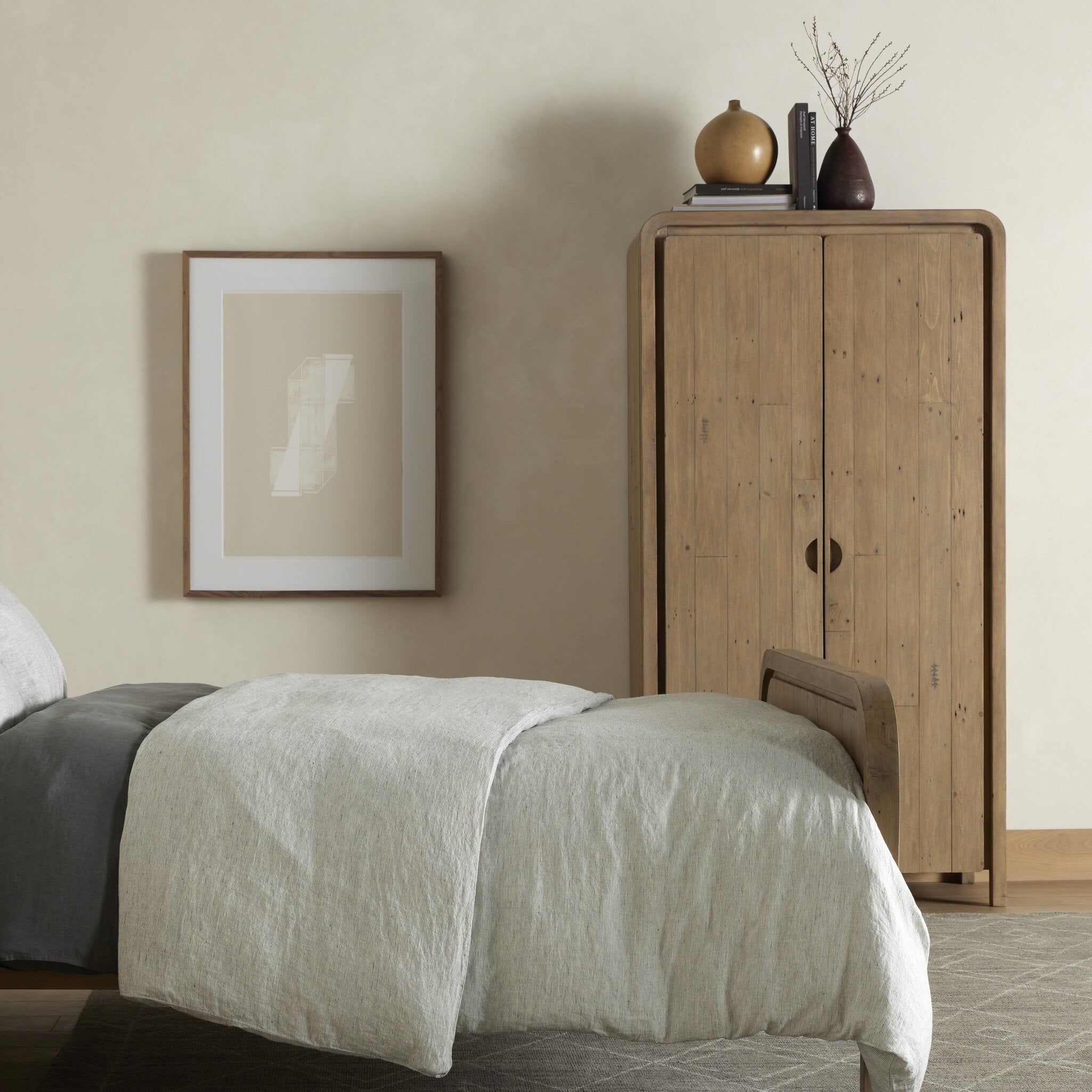 Bedroom with wooden cabinet and framed artwork on beige wall. | Wildwood Home Co.