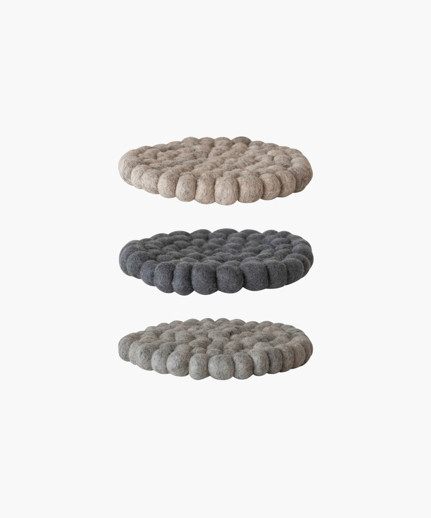 A sideview of 3 Circular felt ball trivet in soft, neutral tones. The textured surface features concentric rings of tightly packed, round felt balls for a cozy, rustic feel. | Wildwood Home Co.