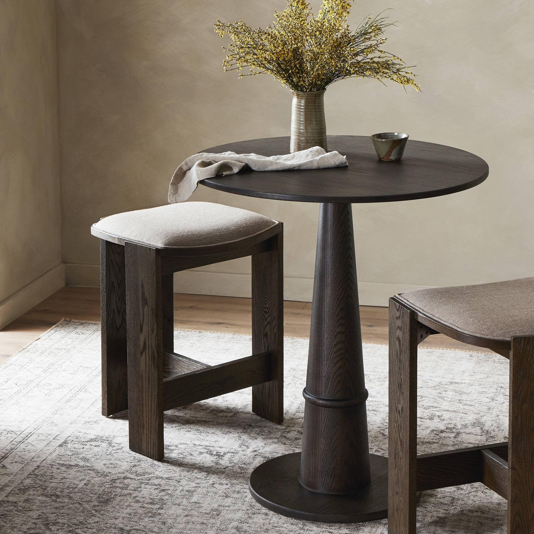 Round wooden table with two stools in a room setting. | Wildwood Home Co.