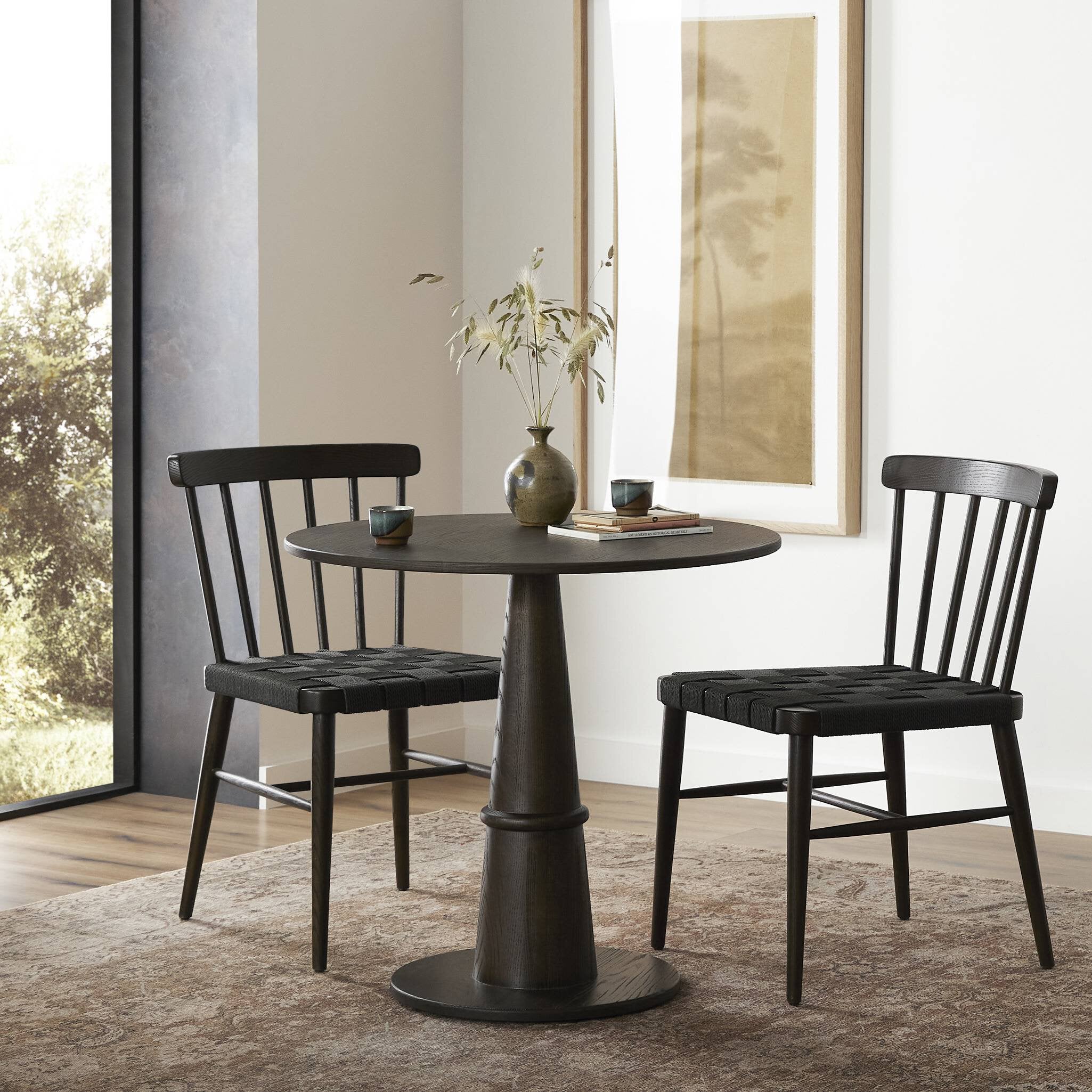 Dining set with black round table and chairs in a room with large windows. | Wildwood Home Co.