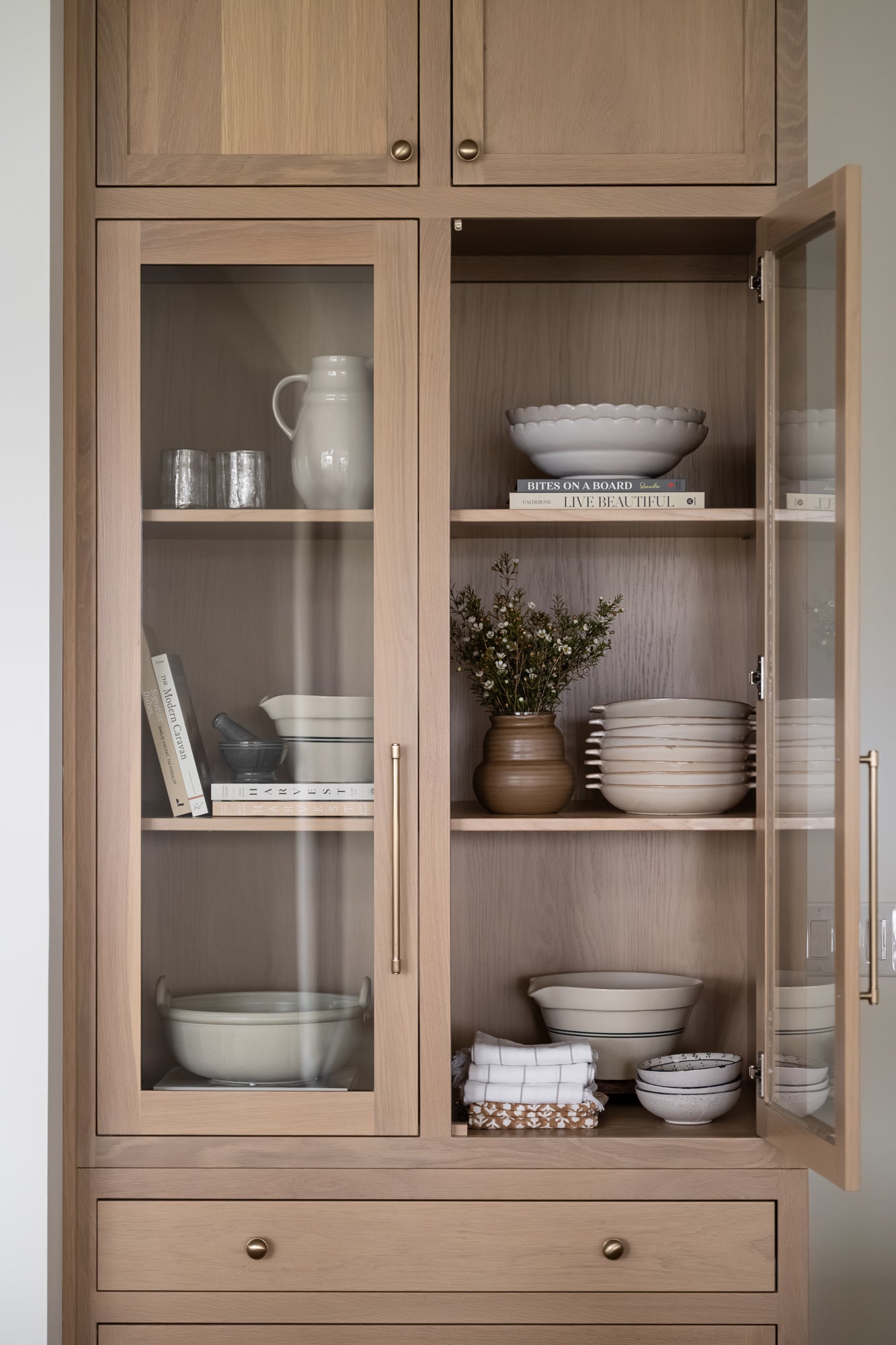 Green bowl with a scalloped edge styled on a shelf with books, bowls, glassware, and a pitcher. | Wildwood Home Co. | Wildwood Home Co.