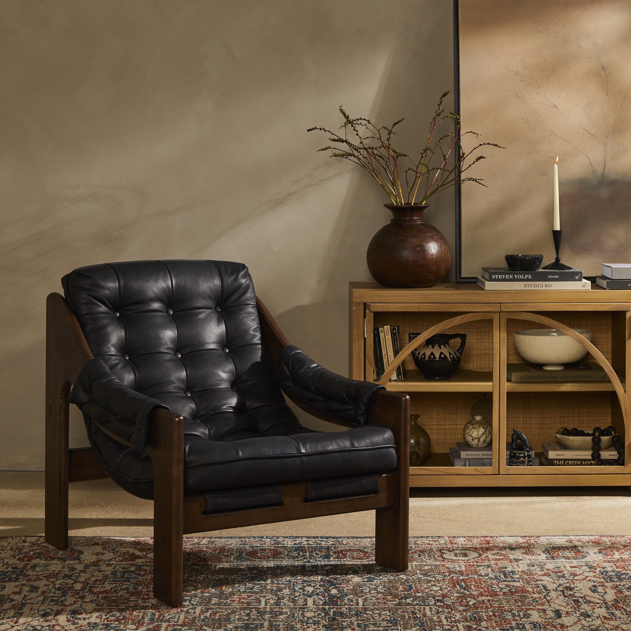 Black leather armchair in a room with a wooden shelf and decorative items. | Wildwood Home Co.