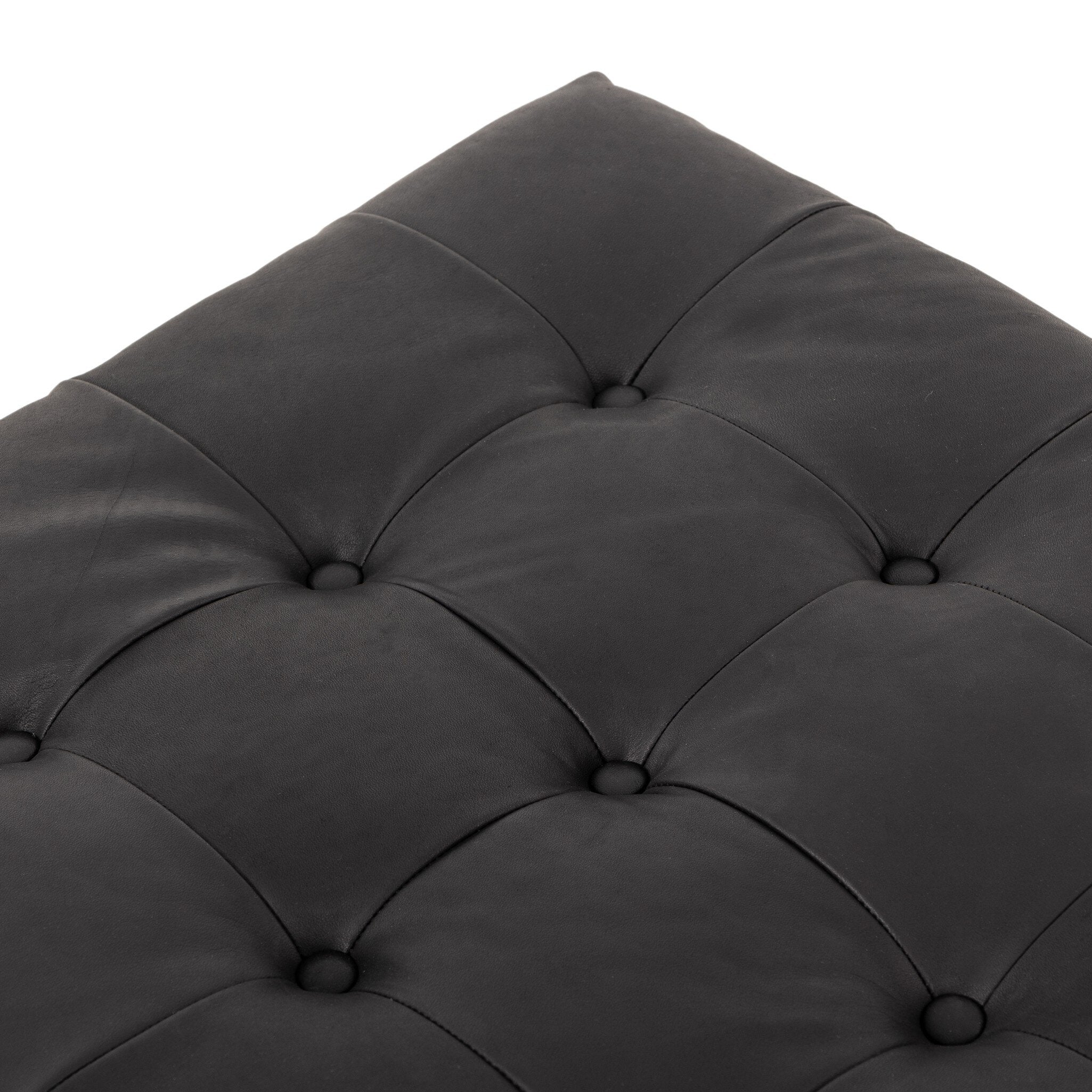Close-up of a tufted black leather cushion on a white background.