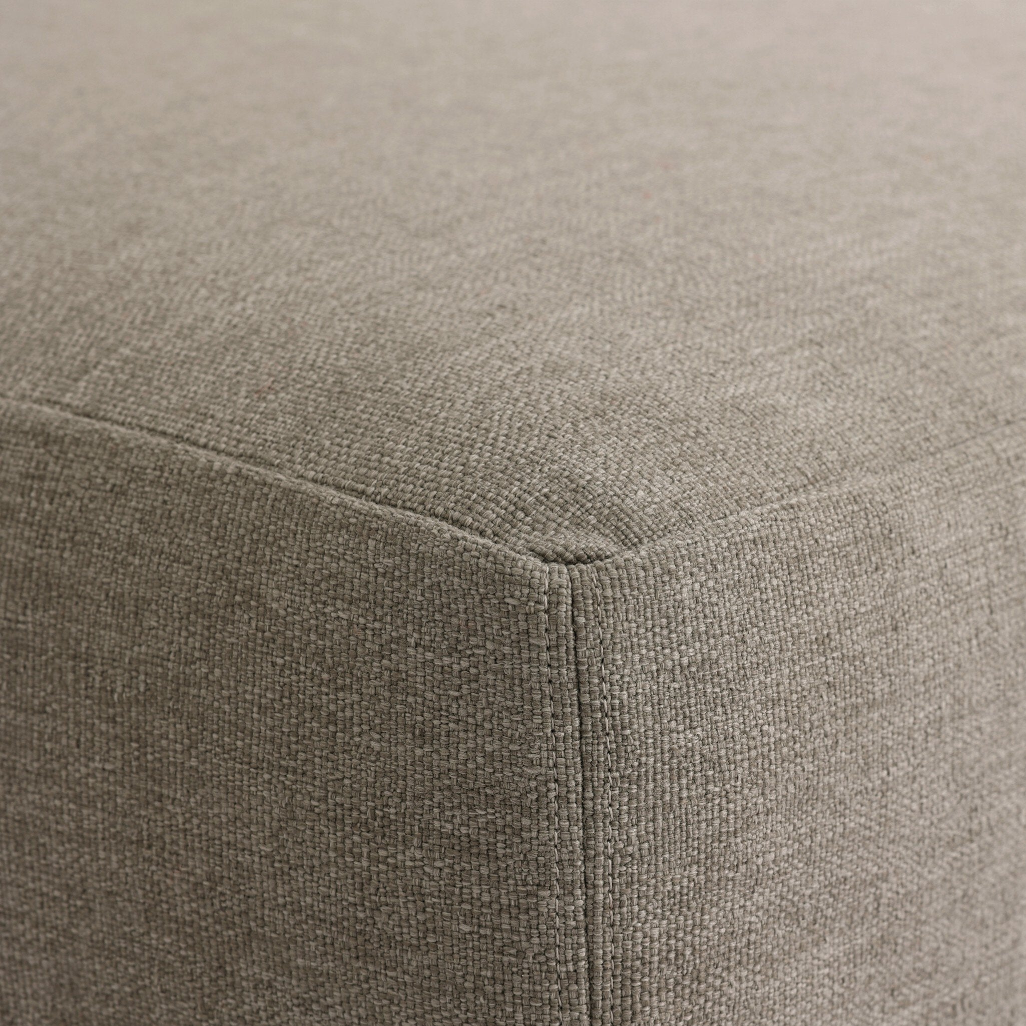 Close up of a slipcover gray outdoor ottoman showing its color and fabric texture. 
