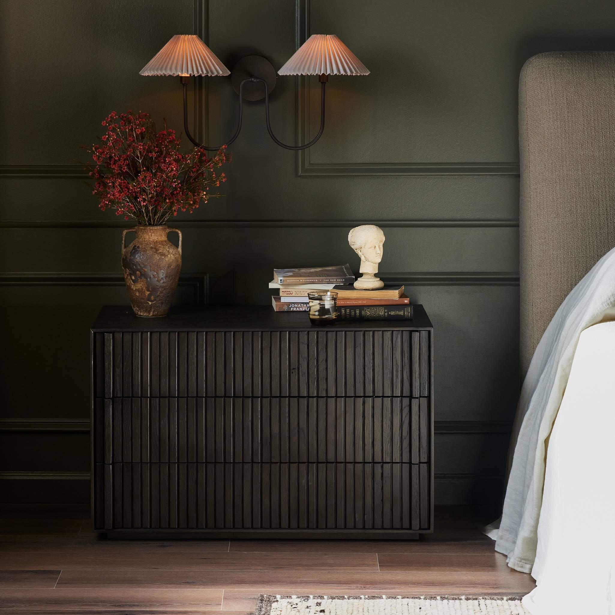 Dark wooden nightstand with decorative items against a dark wall in a bedroom. | Wildwood Home Co.