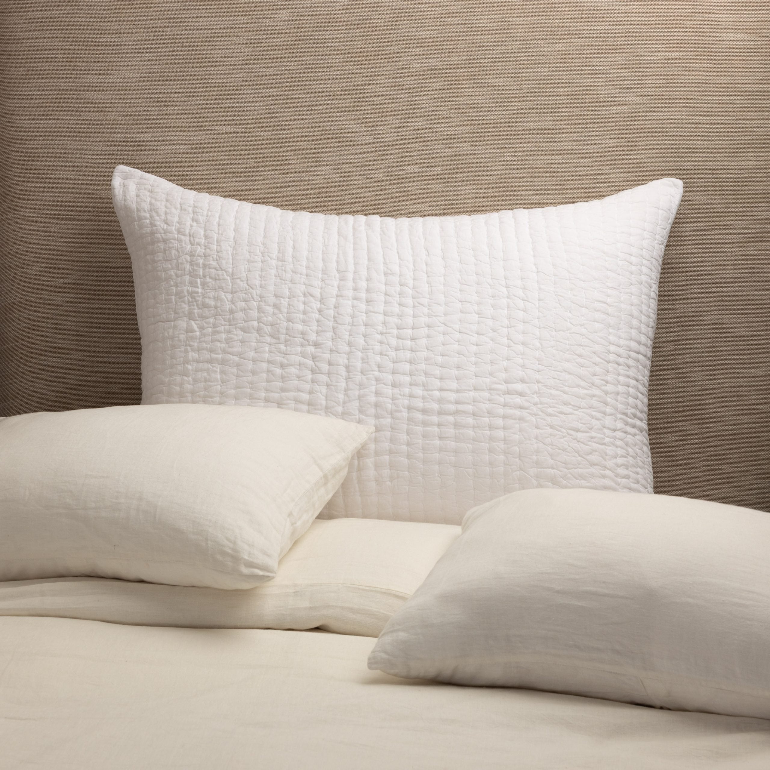 Maegan Sham styled against a neutral headboard with cream linen bedding, showcasing its texture and casual elegance. | Wildwood Home Co.
