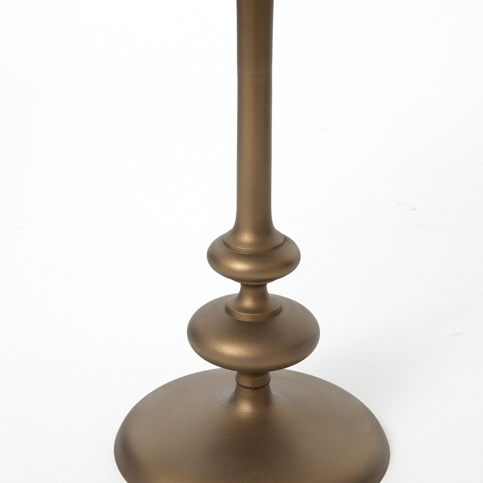 Close up of a brass finished pedestal table  base showing its detail on a white background.