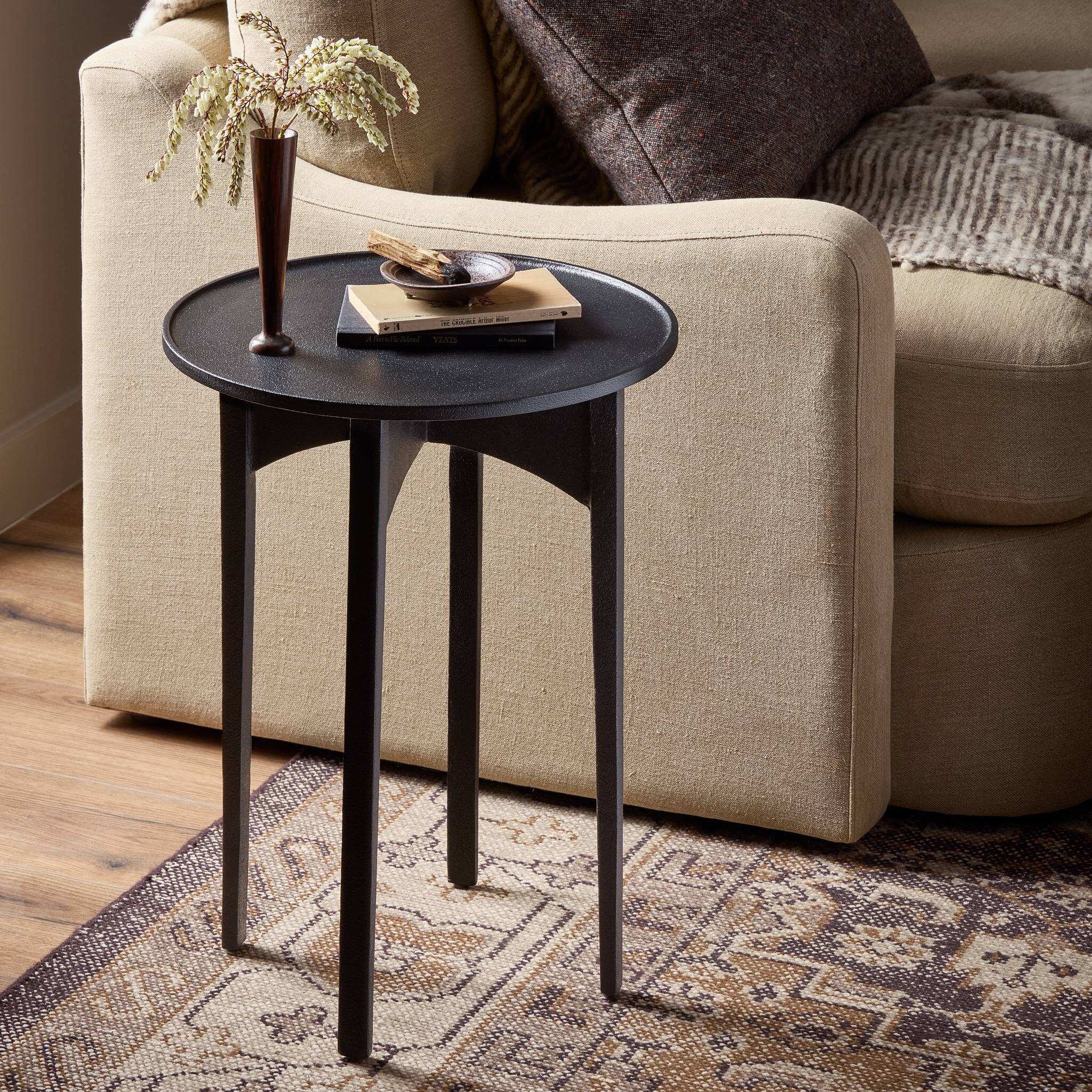 Small black side table with decorative items in front of a beige sofa. | Wildwood Home Co.