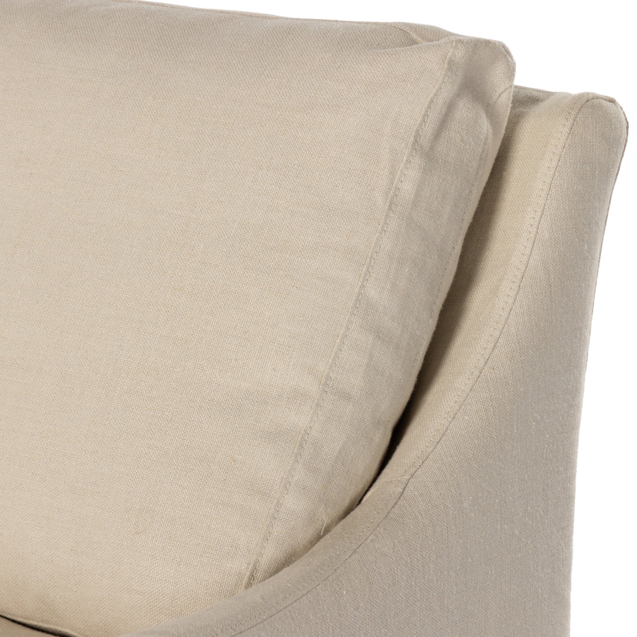 Close up of a traditional swivel chair with an ivory slipcover on a white background. 