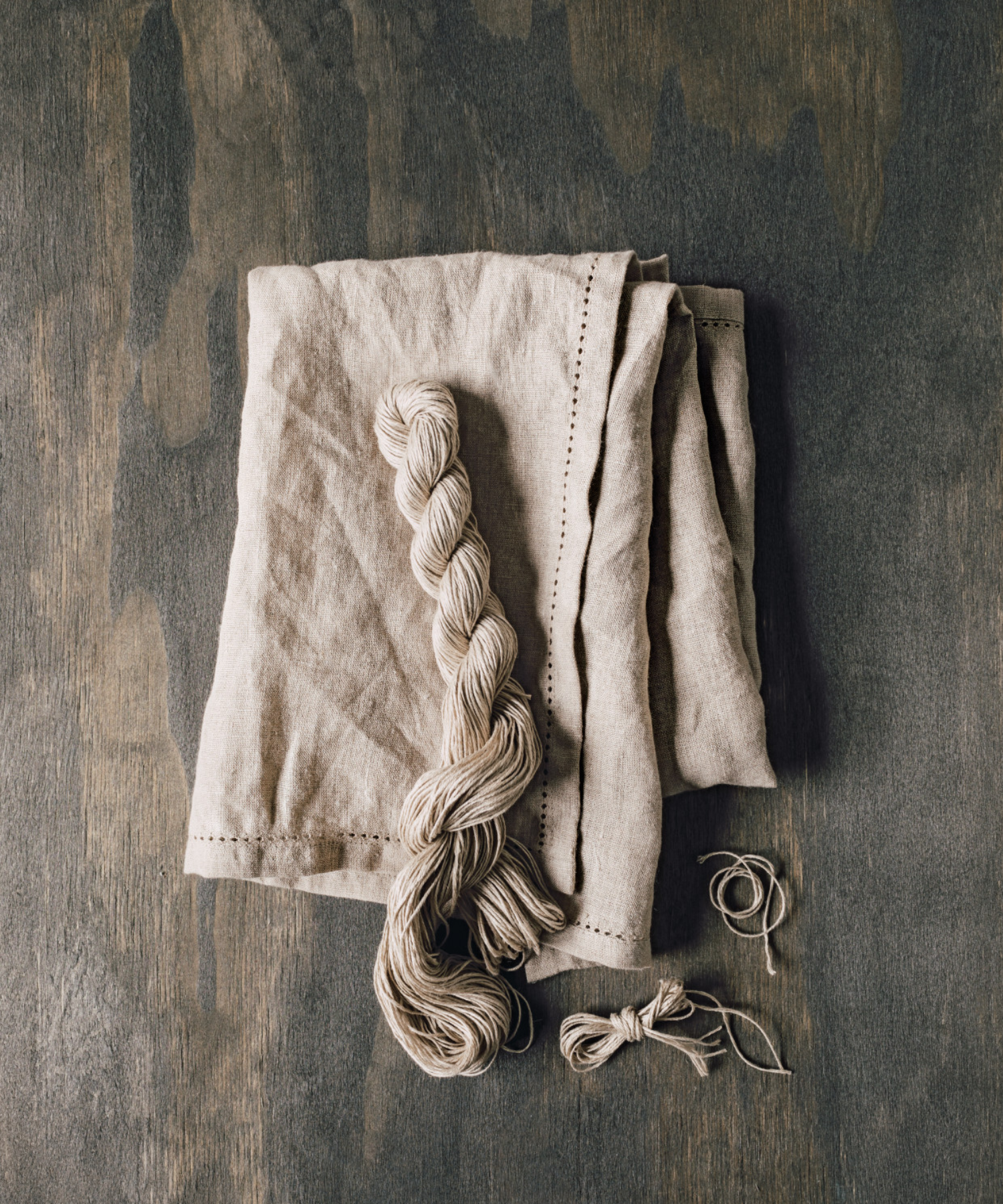 A beige cloth napkin with subtle hemstitch detailing along the edges. It is neatly folded, conveying a sense of elegance and simplicity. | Wildwood Home Co.