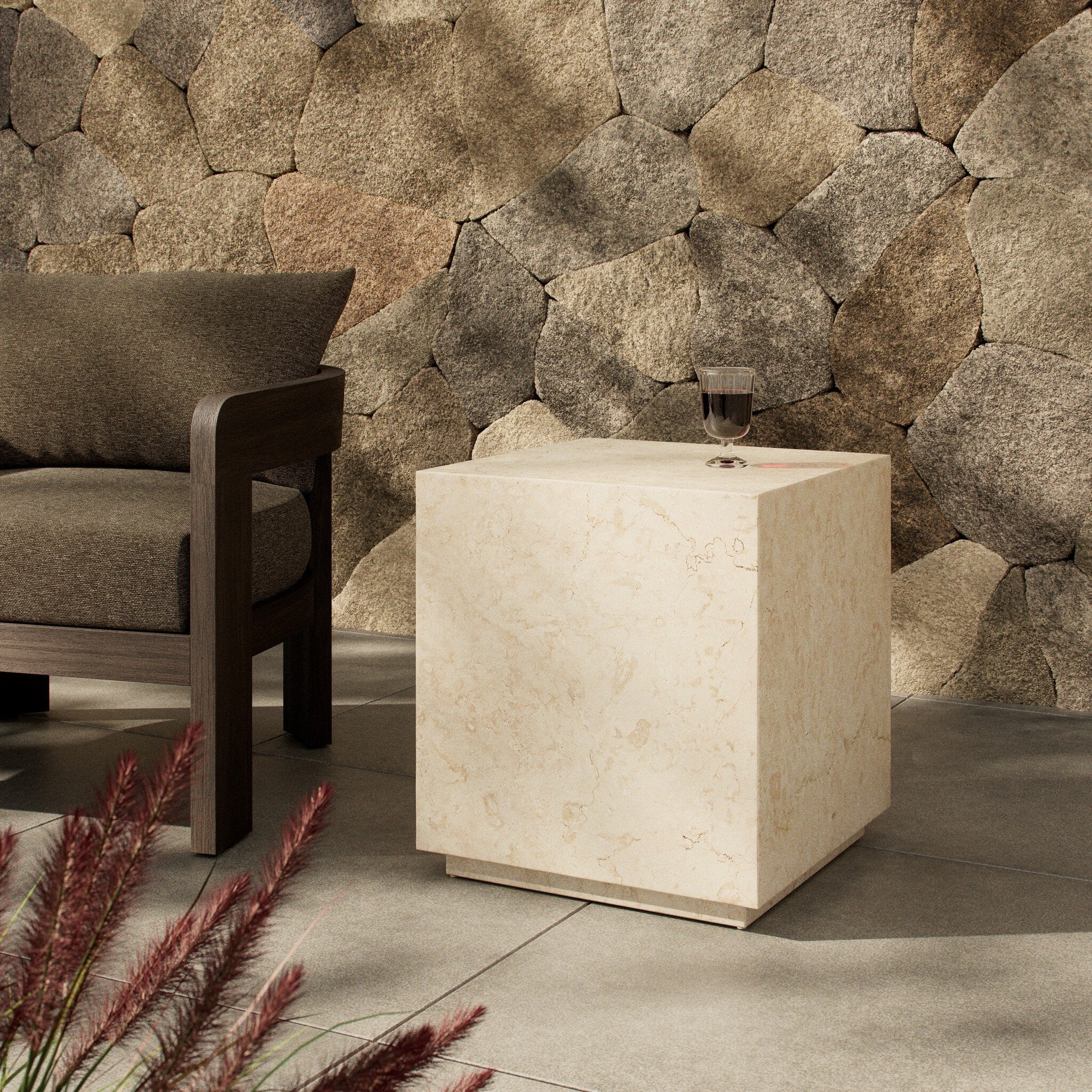 Beige cube-shaped end table against a stone wall with a chair and decorative plants. | Wildwood Home Co.