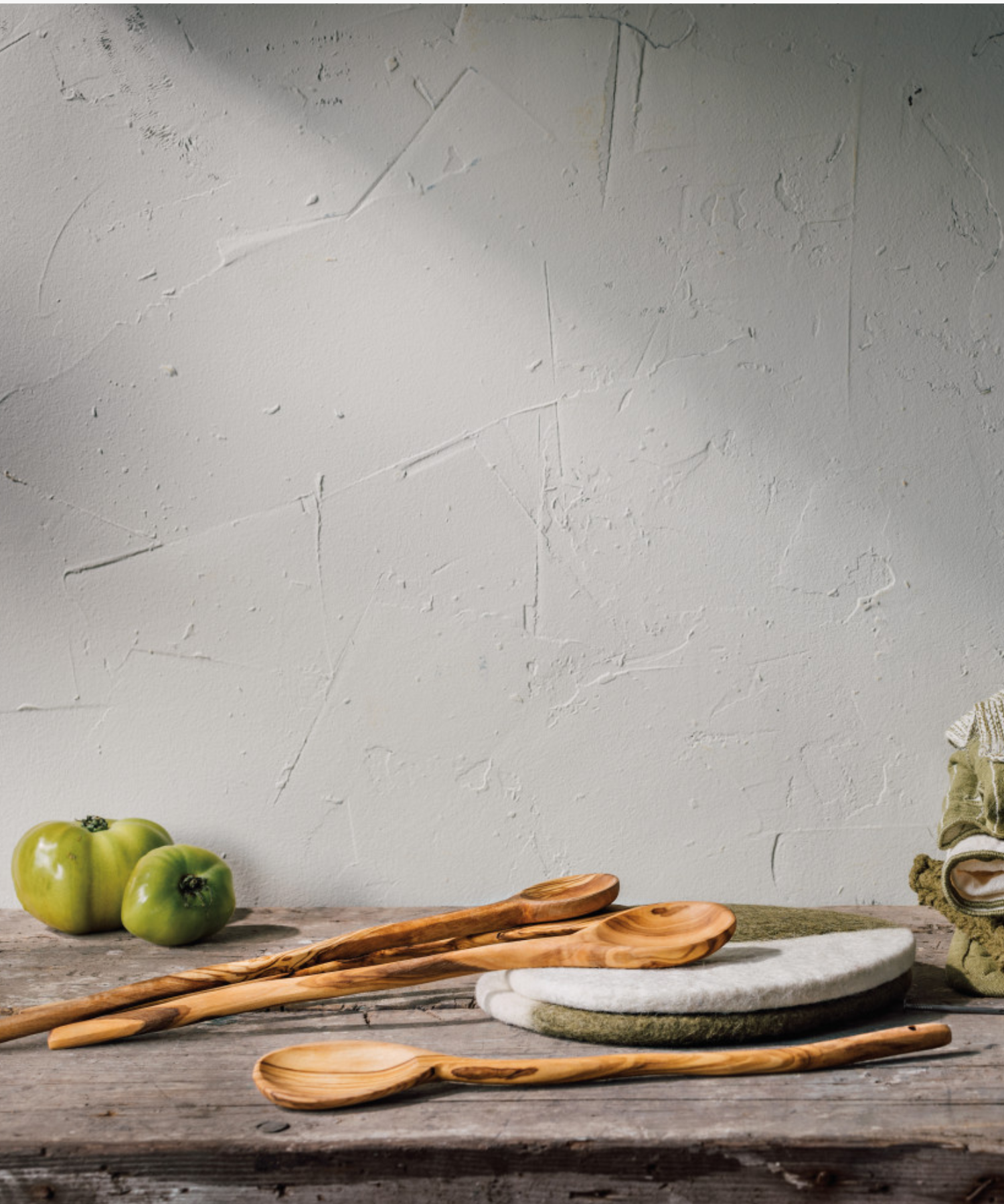 A wooden spoon with a smooth, elongated handle and a round head, featuring natural light and dark brown grain patterns styled with other wood spoons and a rustic table. | Wildwood Home Co.
