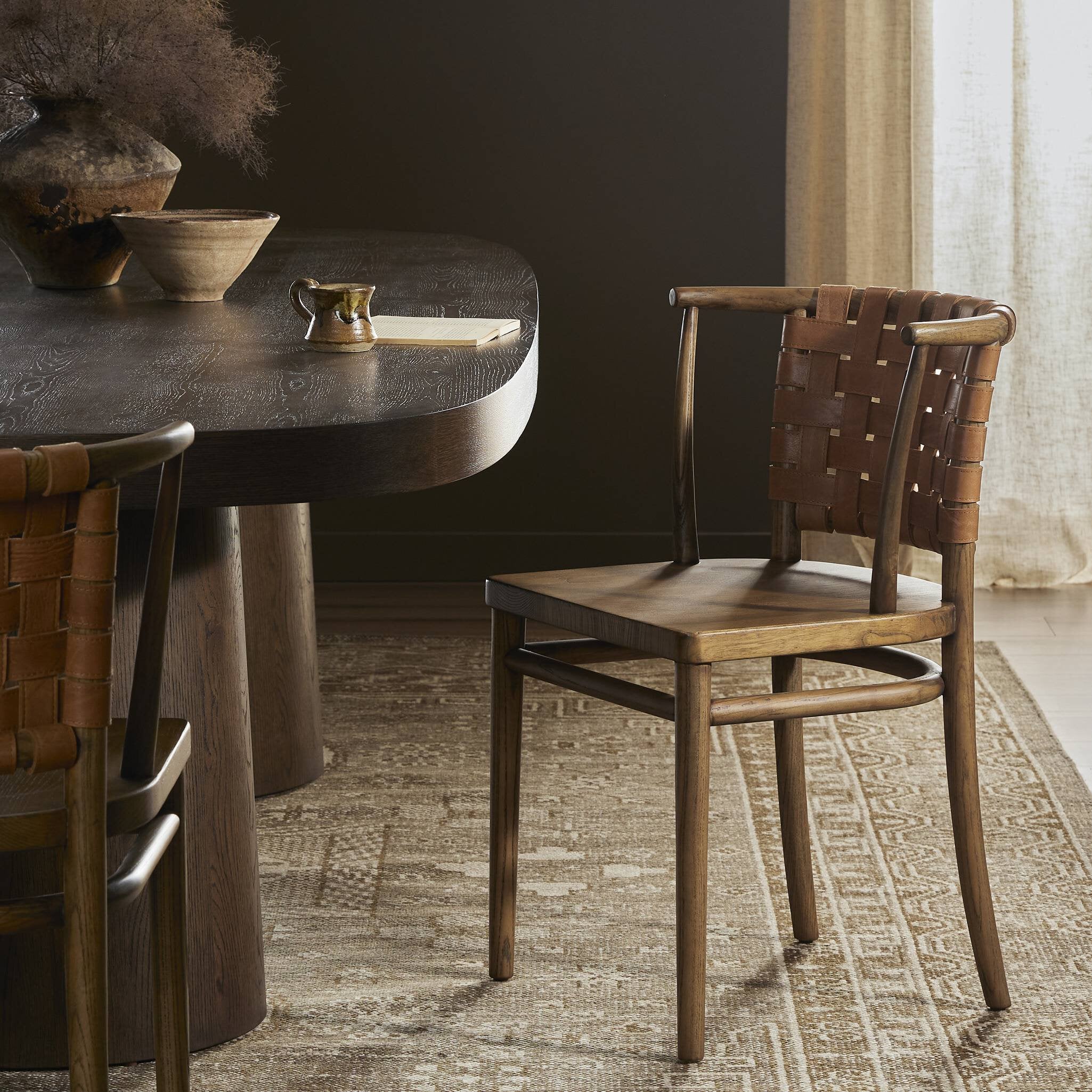 Dining table with woven back chairs on a textured rug. | Wildwood Home Co.