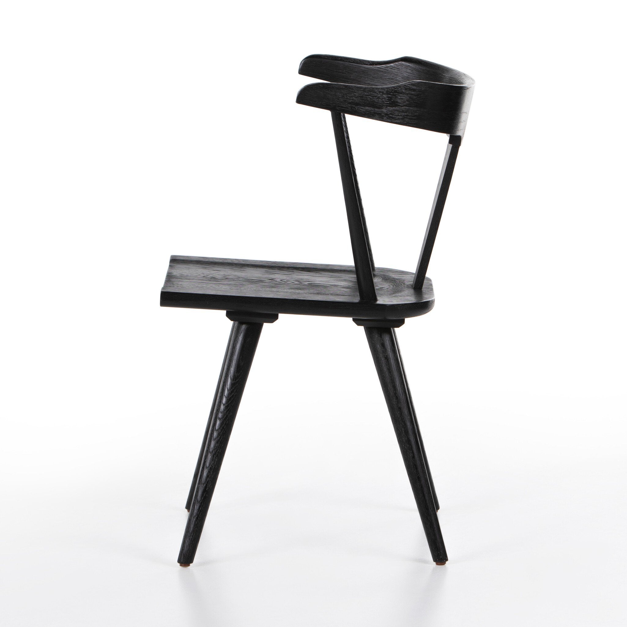 Side profile of a black wooden dining chair on a white background.