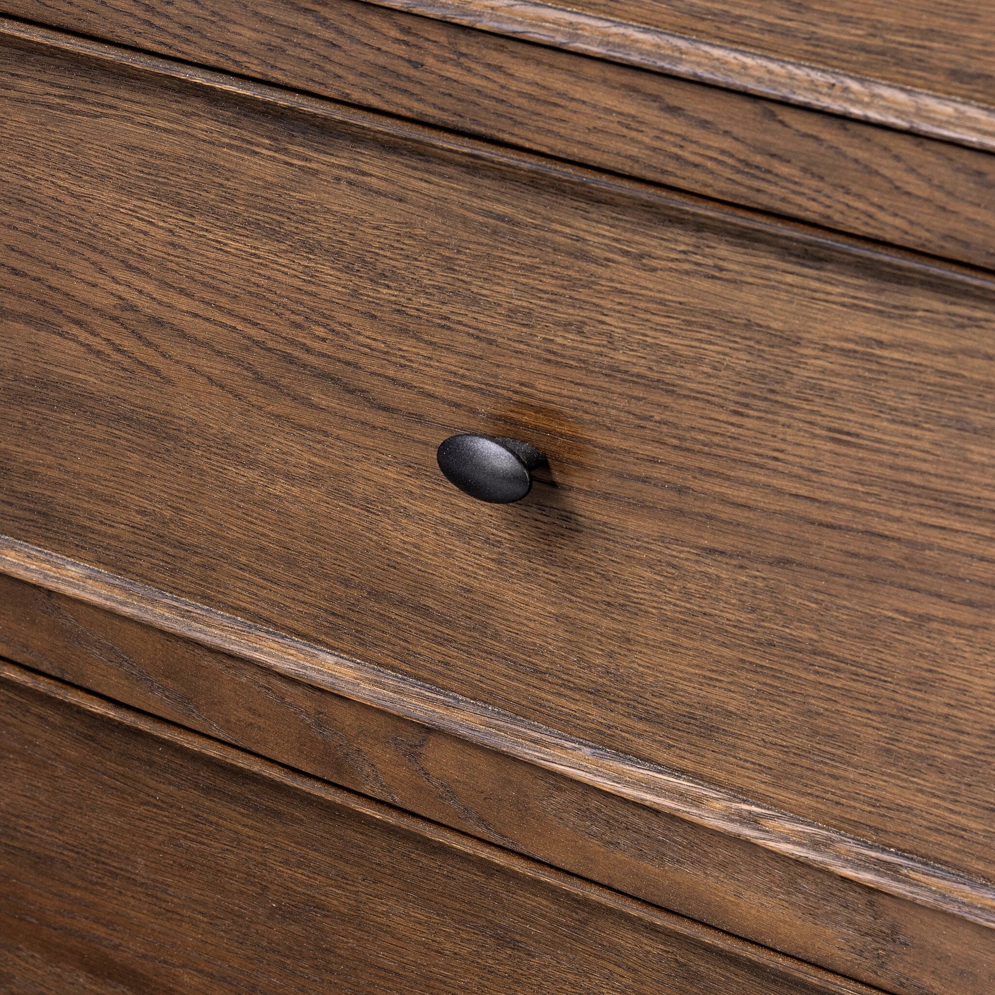 Close up of a wooden dresser with multiple drawers on a white background.