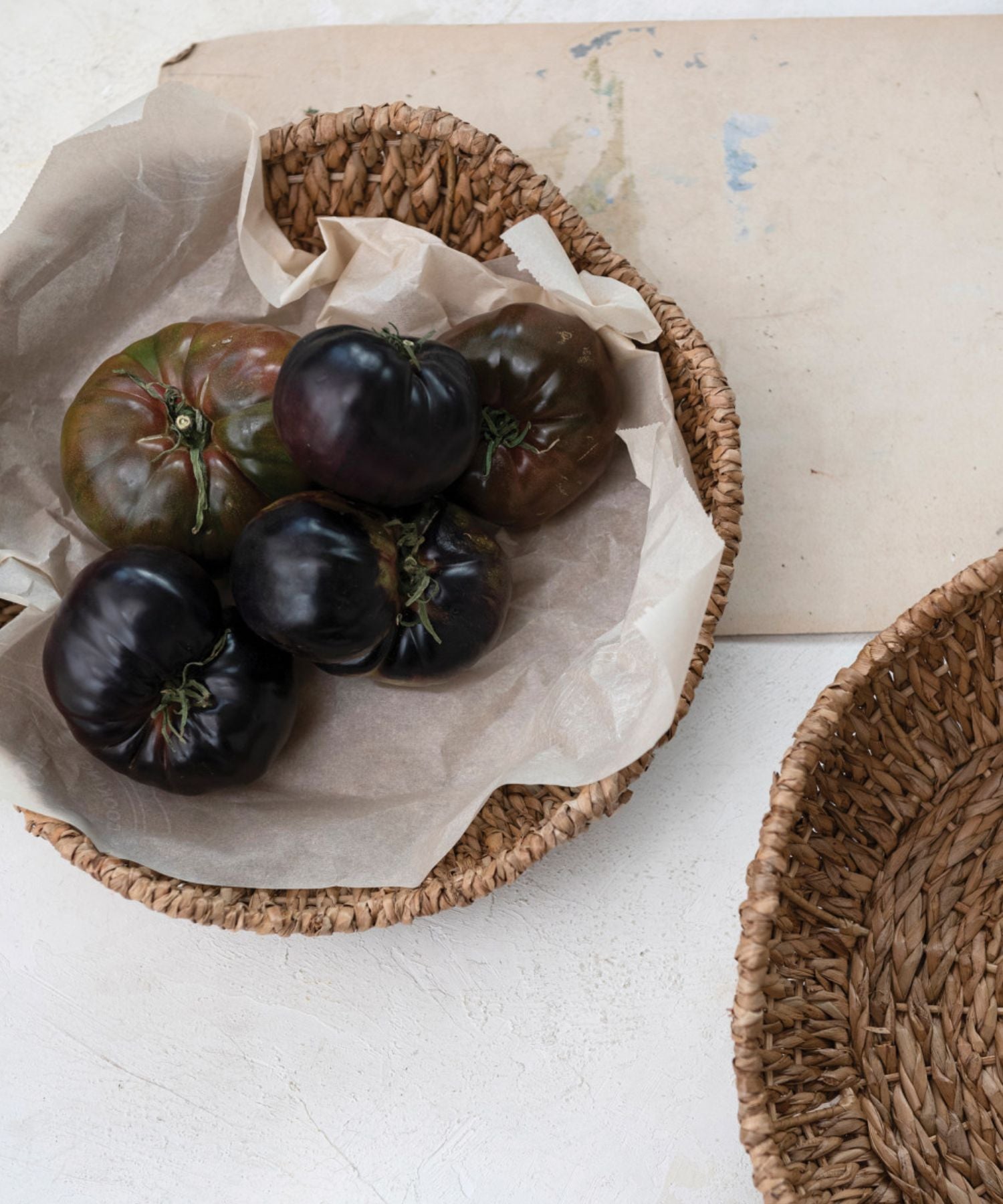 Bankuan woven bowl or basket with a scalloped edge styled with tomatoes and marble cutting board. The earthy tone conveys a rustic, organic feel.