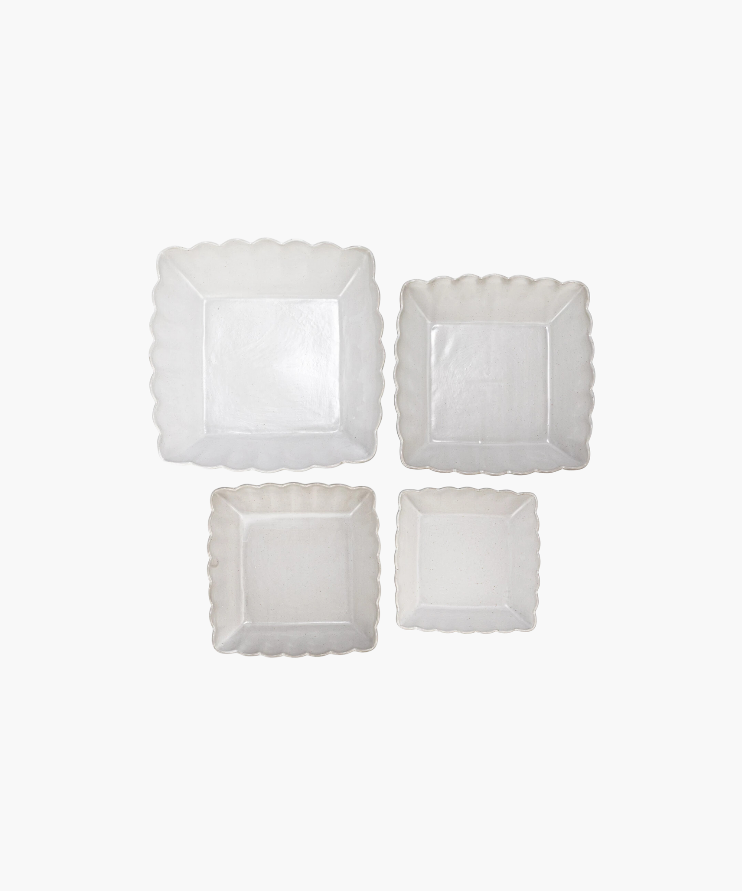 Four white ceramic dishes of various sizes with scalloped edges and a subtle, glossy finish. The dish is empty and set against a plain white background. | Wildwood Home Co.