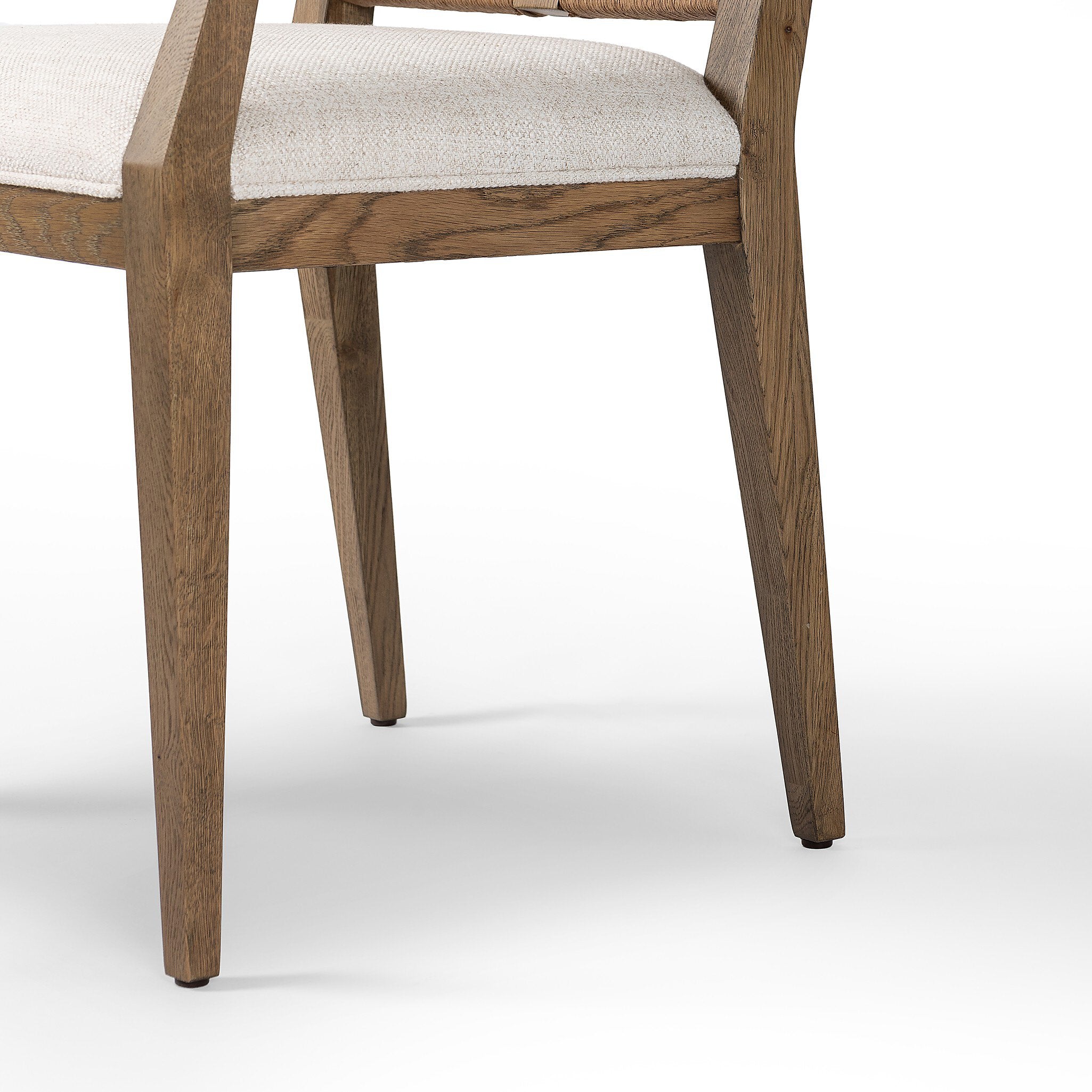 Close up of a wooden dining arm chair with woven backrest and white cushion on a white background.
