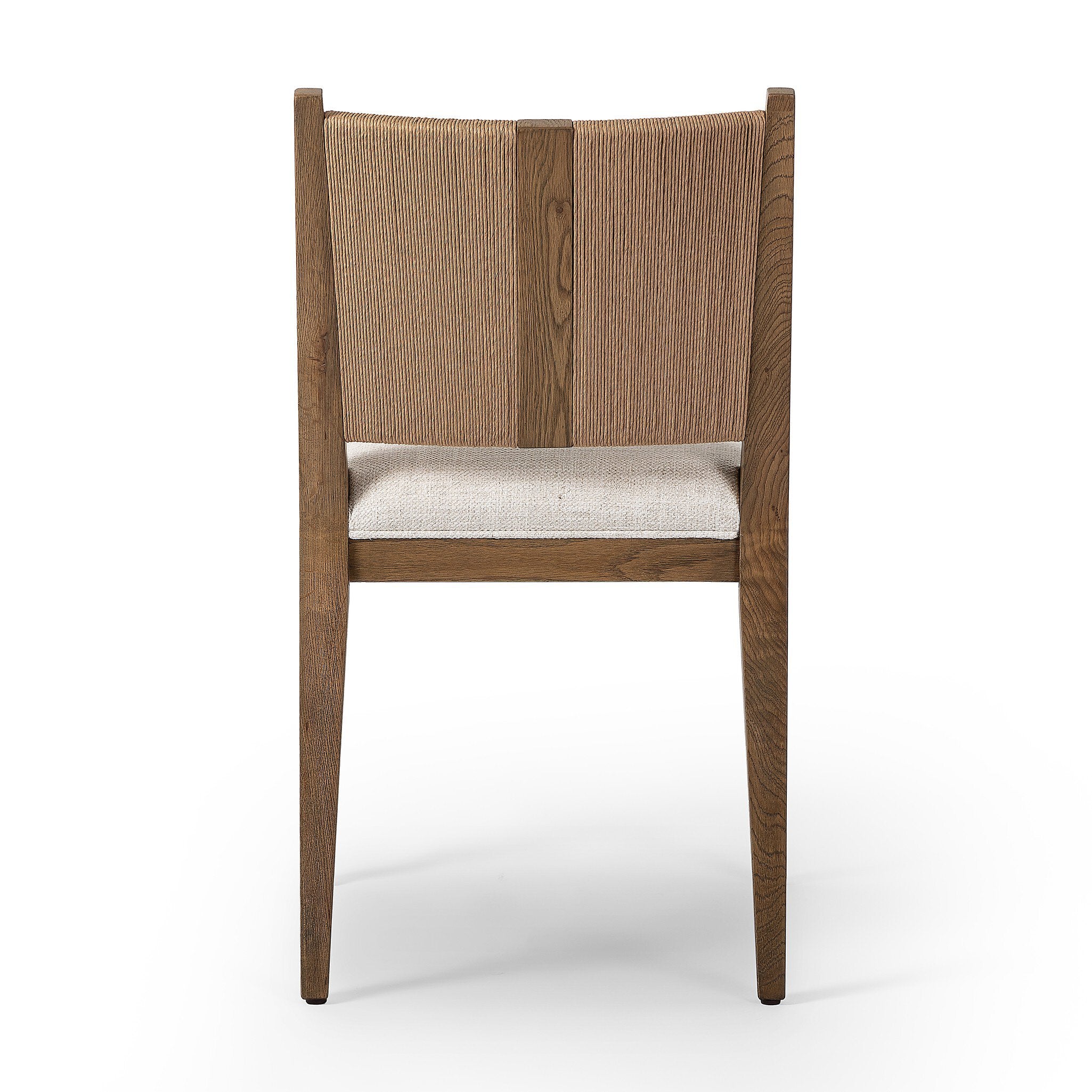 The back of a wooden dining chair with a woven backrest and white cushion on a white background