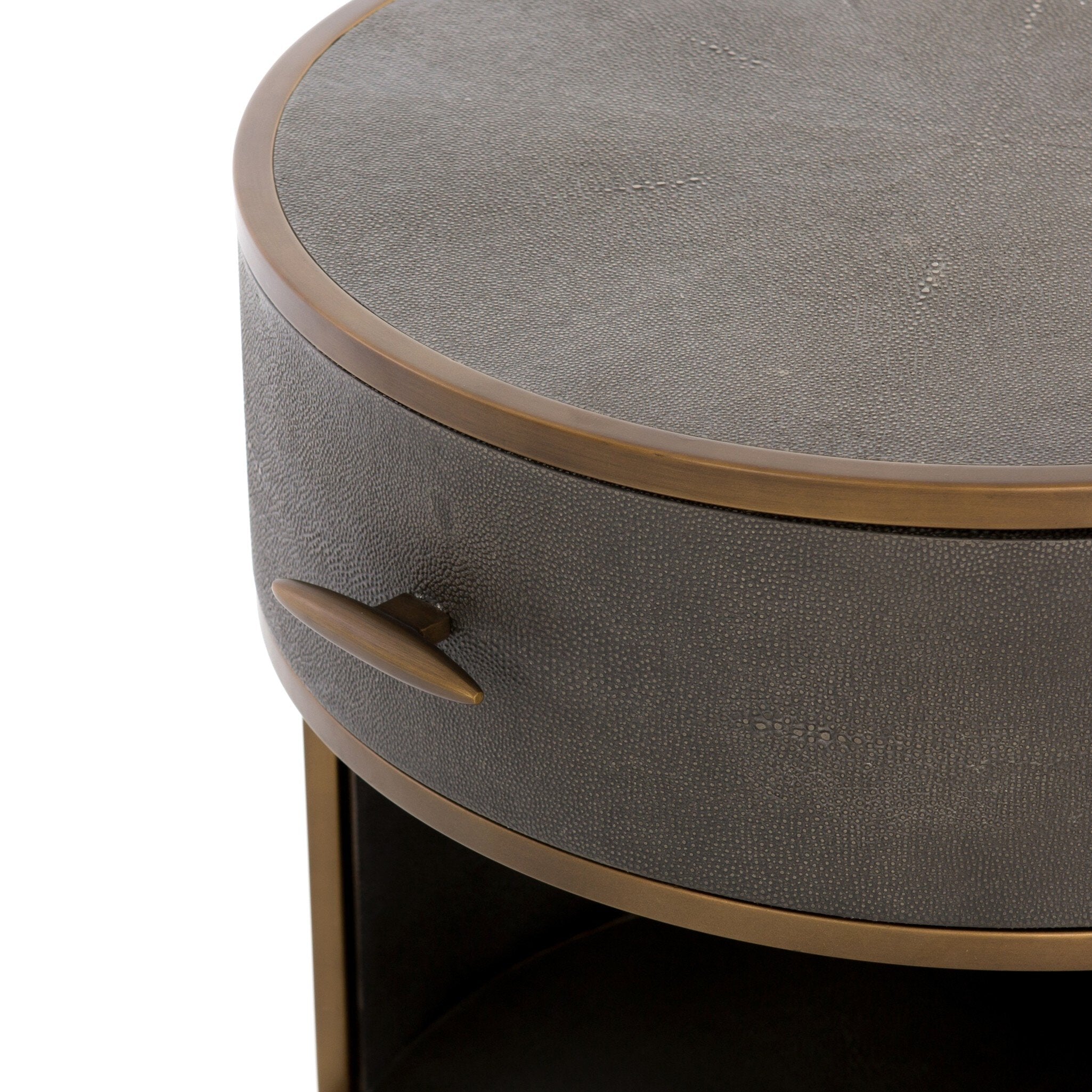 A close up of a round side table with a drawer and brass legs on a white background.