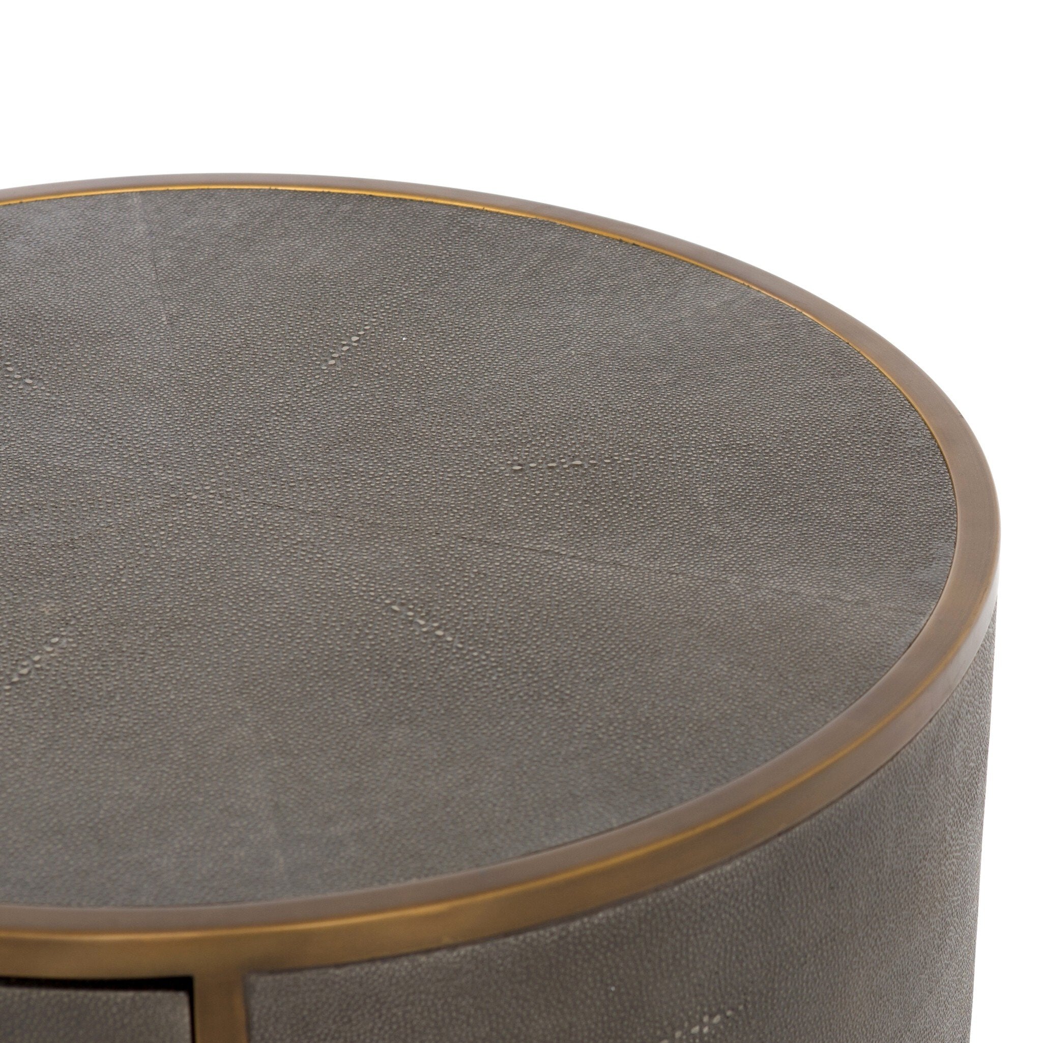 A close up of a round side table with a drawer and brass legs on a white background.