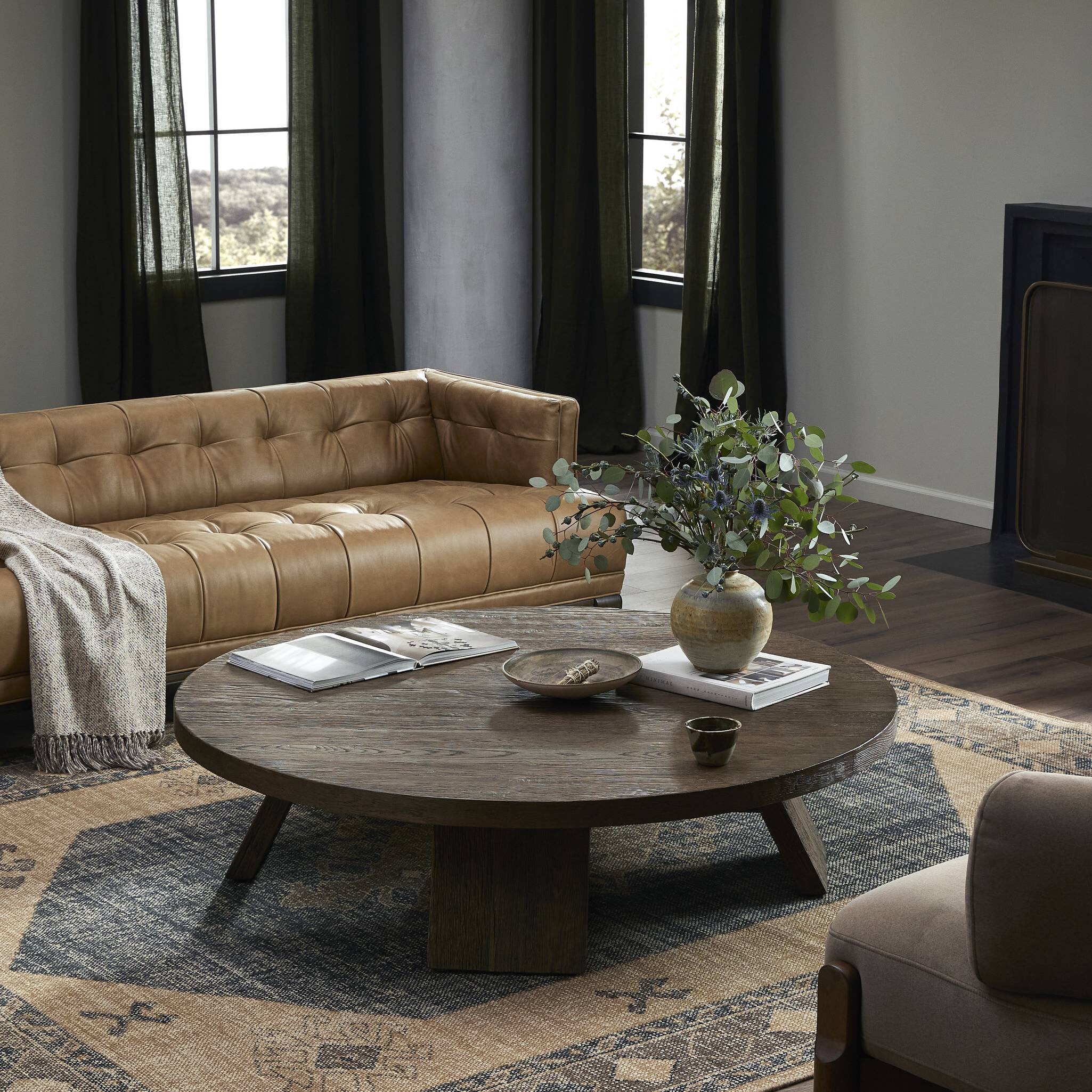Living room with brown leather sofa, round wooden coffee table, and decorative elements.