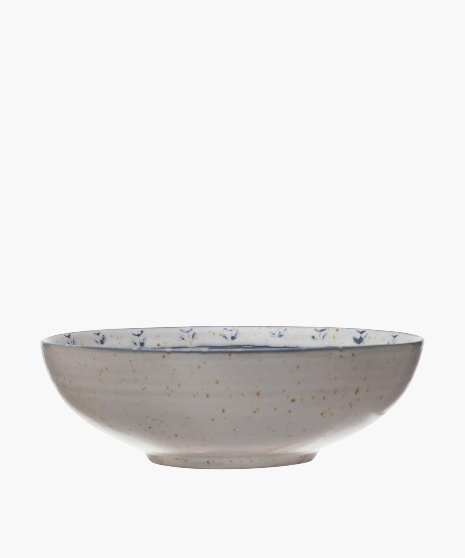 A speckled ceramic bowl with blue floral patterns inside. The off-white surface and wide, shallow shape give a rustic, elegant feel. | Wildwood Home Co.