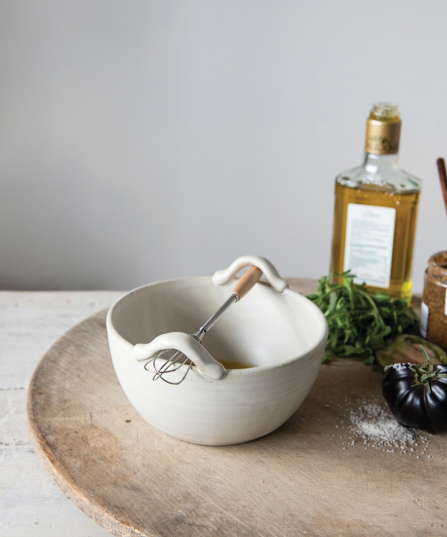 A cream colored stoneware ceramic mixing bowl with a metal whisk styled with kitchen ware. Evoking a clean, minimalist aesthetic. | Wildwood Home Co.